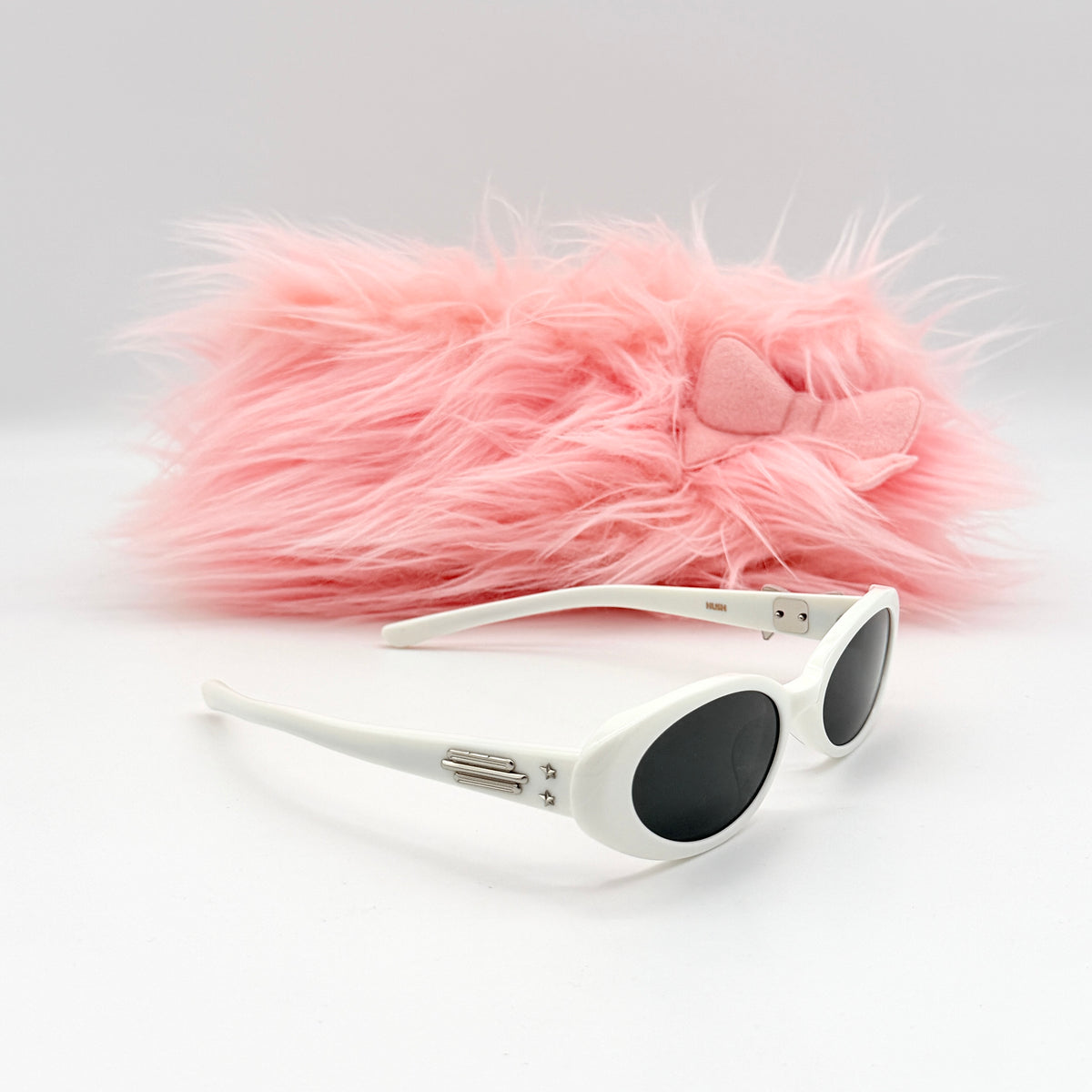 Gentle Monster x Jennie Hush W2 oval sunglasses in white with a pink bow charm, styled with the signature pink furry case.