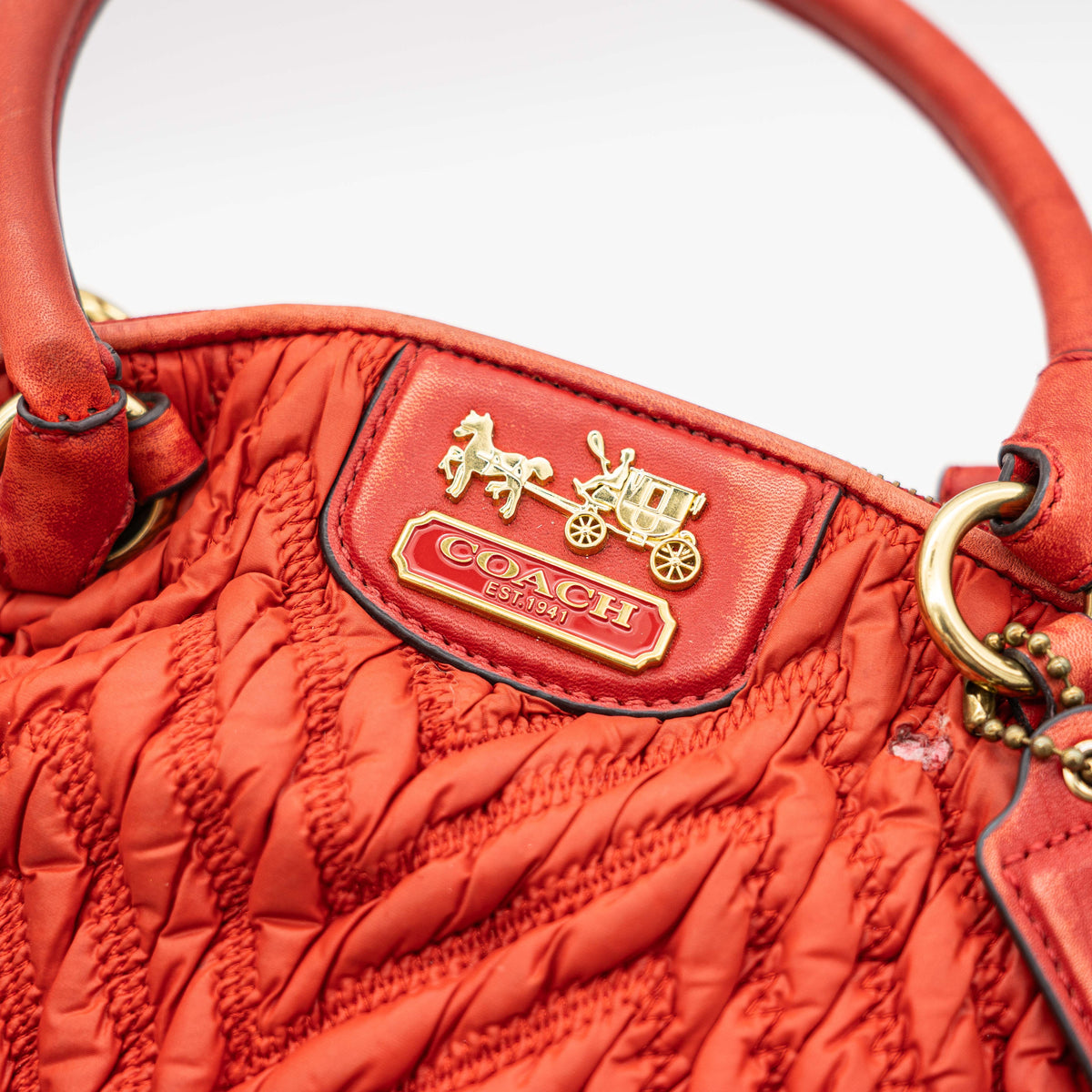 Coach Madison 2Way shoulder bag in rich red quilted texture with gold hardware, top handles, and detachable strap, displayed on a white background.