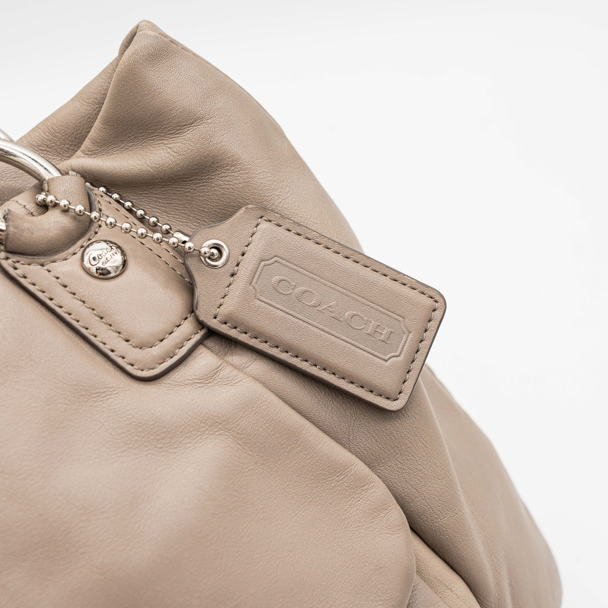 Coach Kristin East West Shoulder Bag in beige leather with silver-tone hardware and double handles.