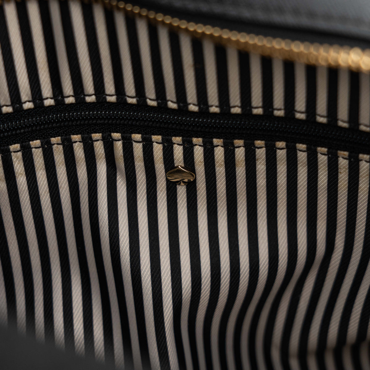 Kate Spade Cameron Street Little Babe satchel in black and white leather with gold hardware, shown with dual handles against a minimal background.