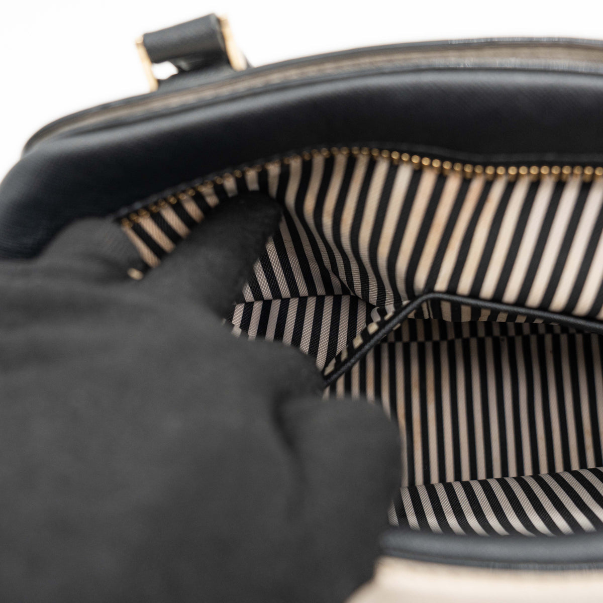 Kate Spade Cameron Street Little Babe satchel in black and white leather with gold hardware, shown with dual handles against a minimal background.