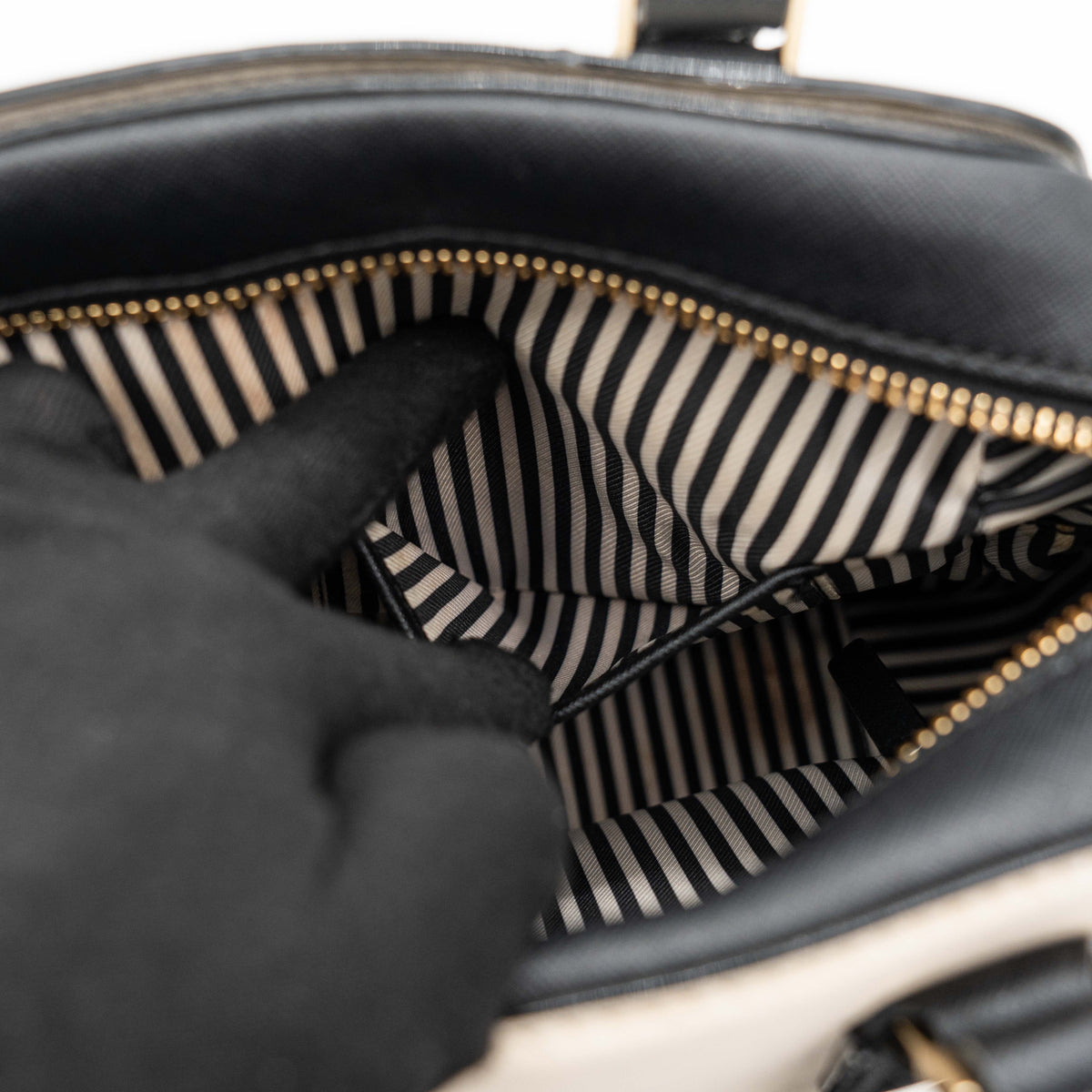 Kate Spade Cameron Street Little Babe satchel in black and white leather with gold hardware, shown with dual handles against a minimal background.