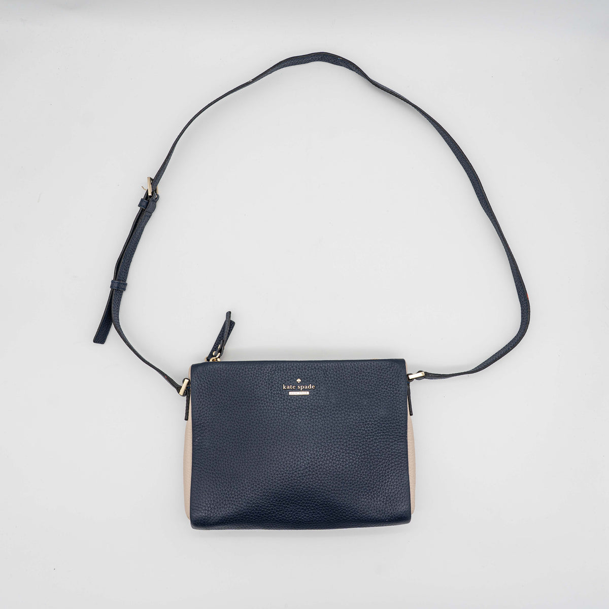 Kate Spade navy blue crossbody bag in pebbled leather, shown with adjustable strap and gold-tone accents.