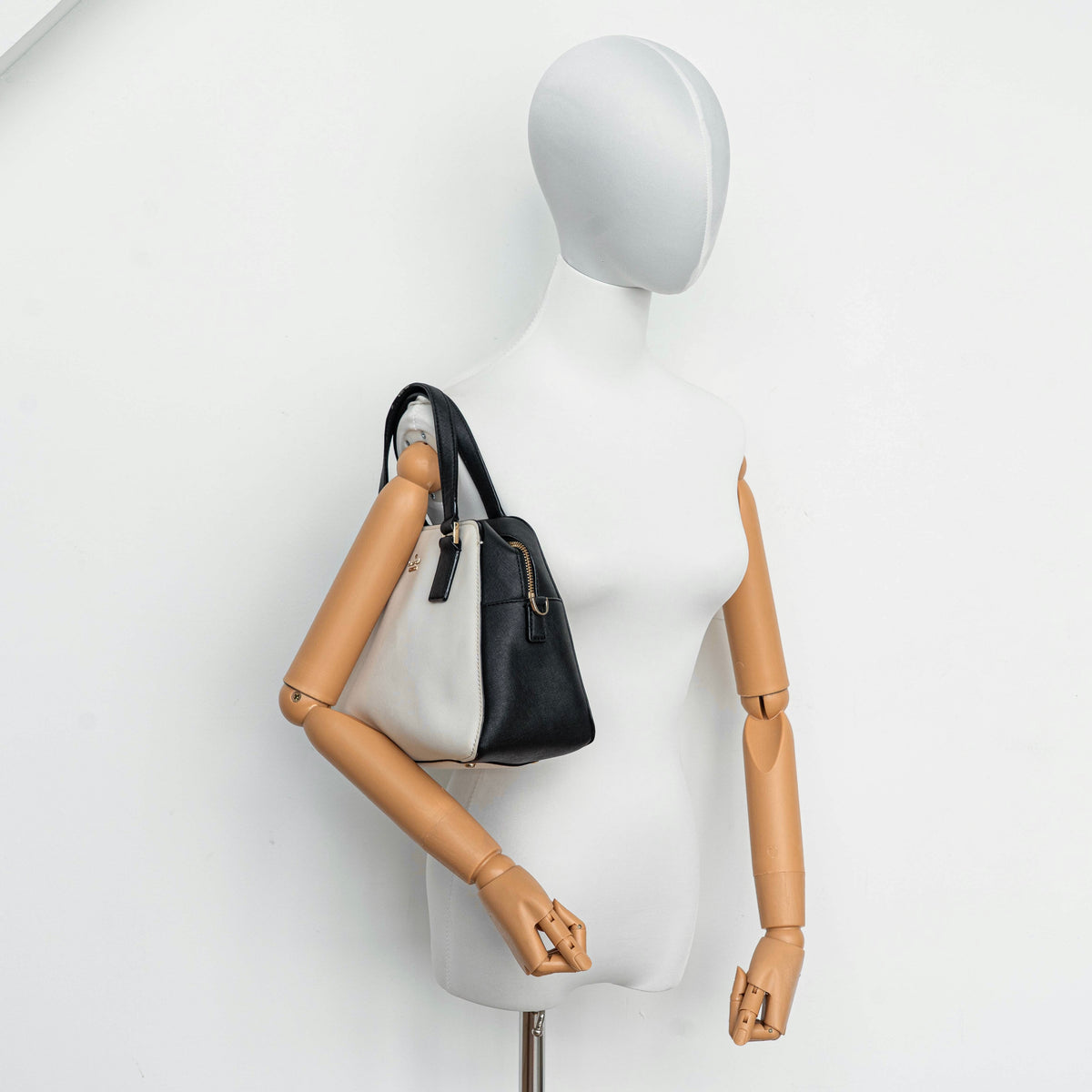 Kate Spade Cameron Street Little Babe satchel in black and white leather with gold hardware, shown with dual handles against a minimal background.