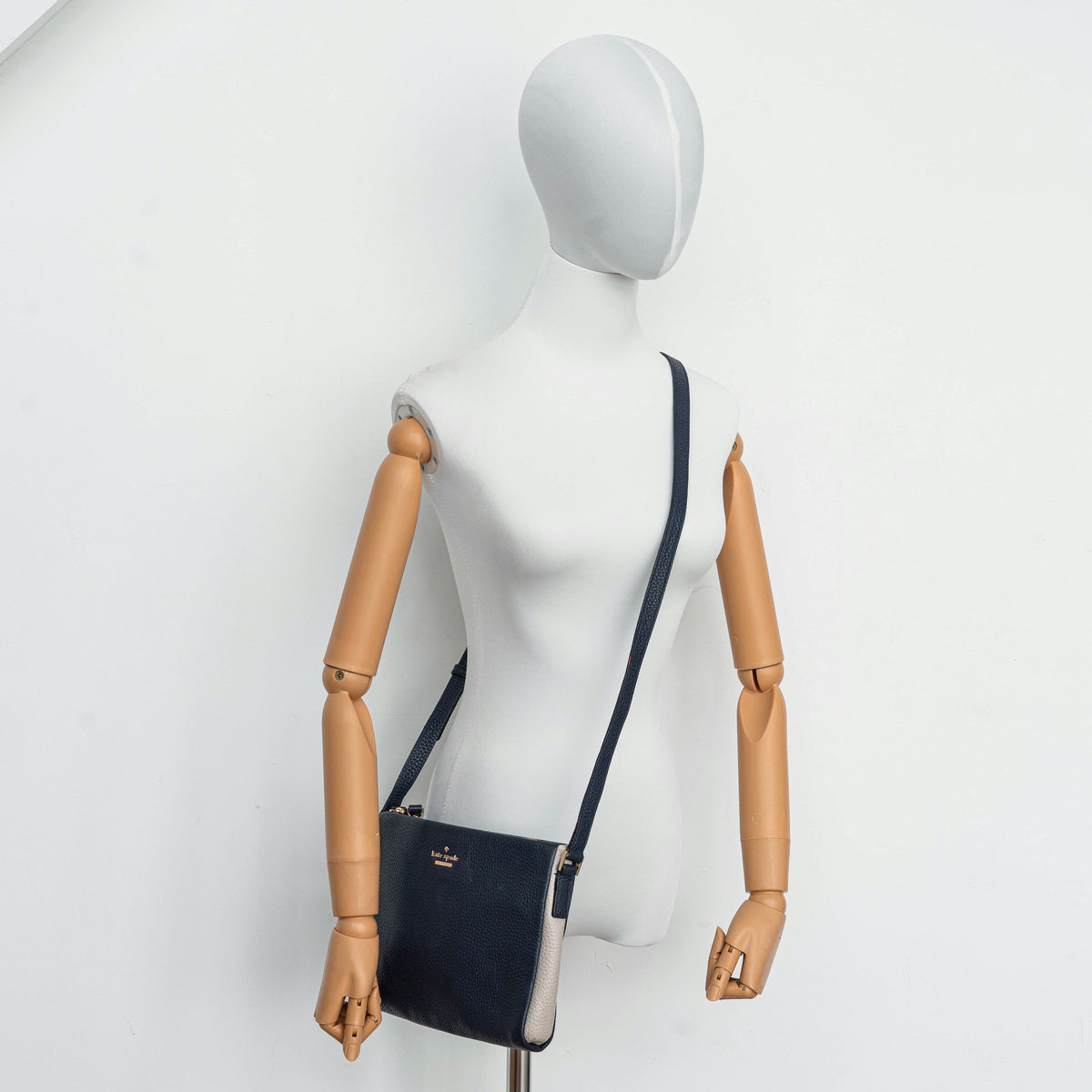 Kate Spade navy blue crossbody bag in pebbled leather, shown with adjustable strap and gold-tone accents.
