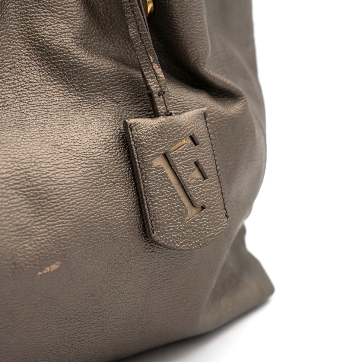 Furla taupe leather shoulder bag with gold hardware and braided detailing, photographed against a white background.