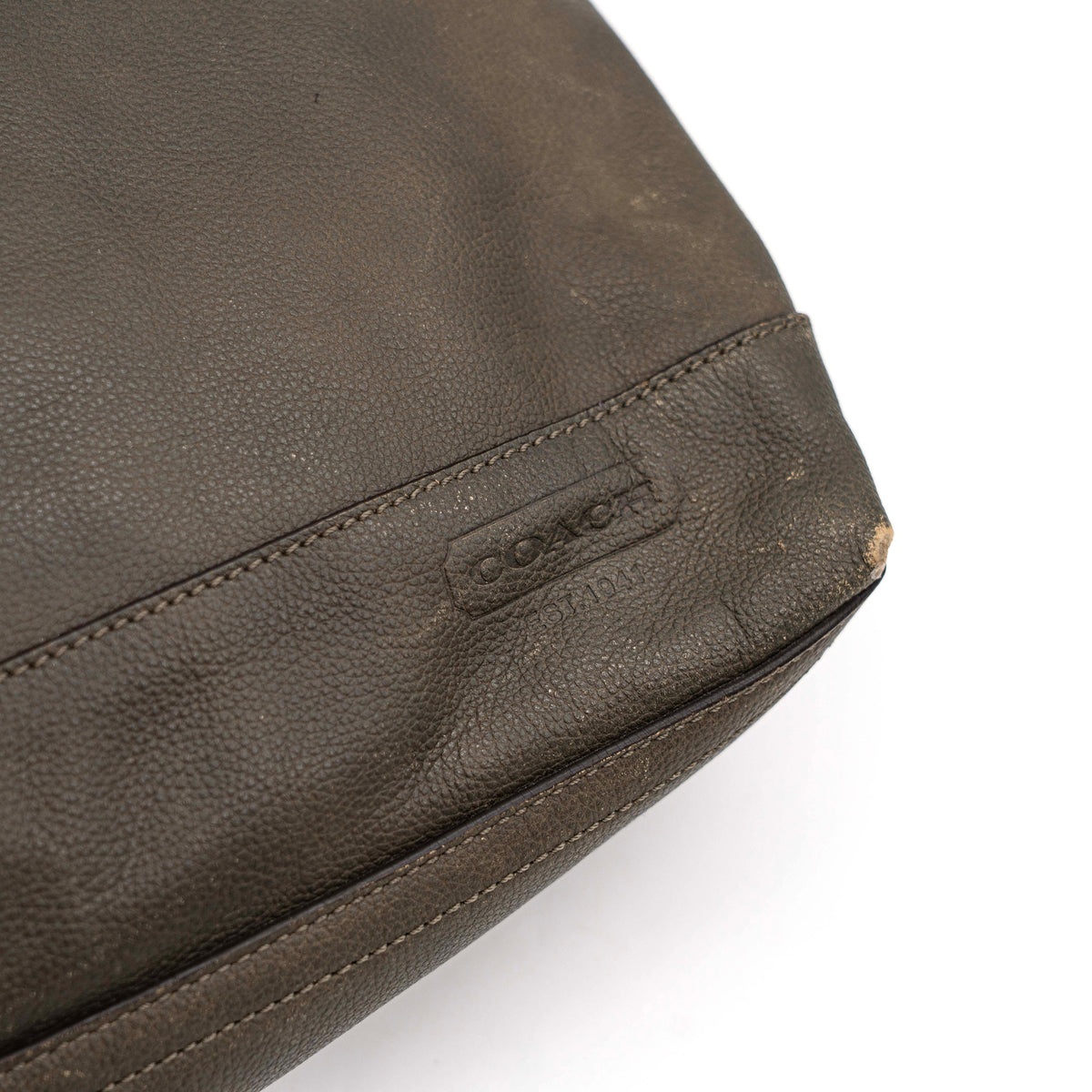 Coach brown leather tote bag with double handles and front zip pocket, shown on a white background.