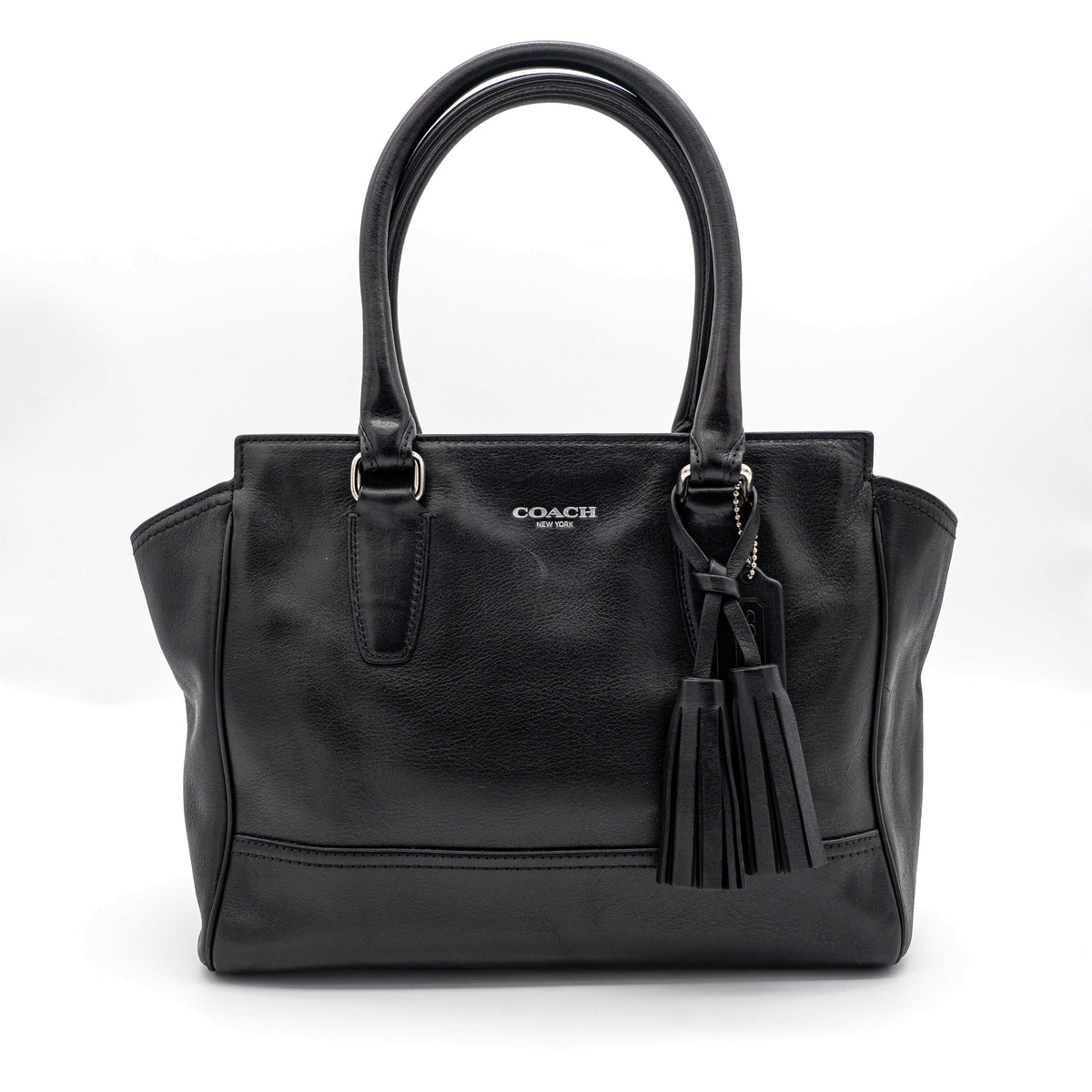 Coach Legacy Candace Carryall in black leather with double tassel charm and silver hardware, photographed against a white background.