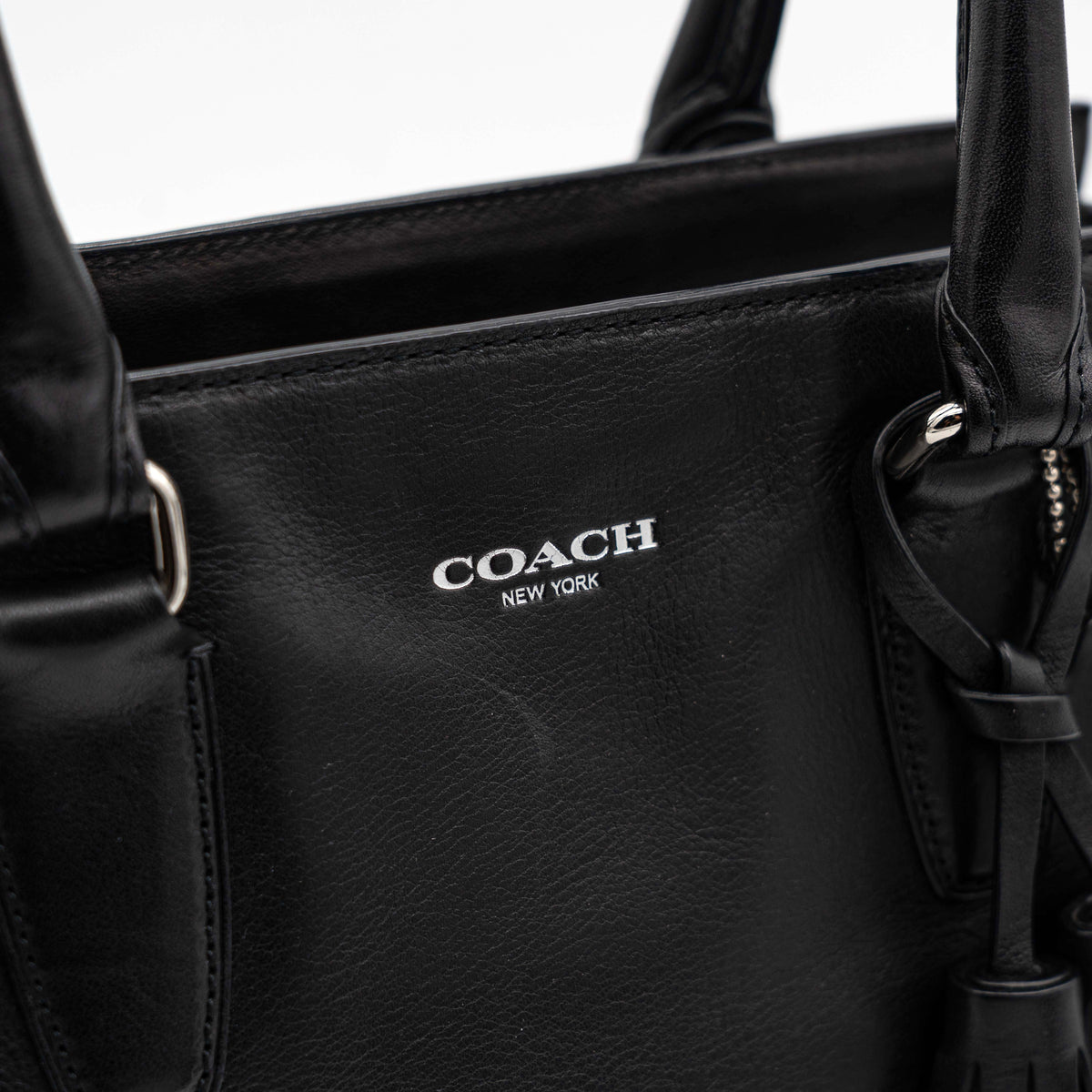 Coach Legacy Candace Carryall in black leather with double tassel charm and silver hardware, photographed against a white background.
