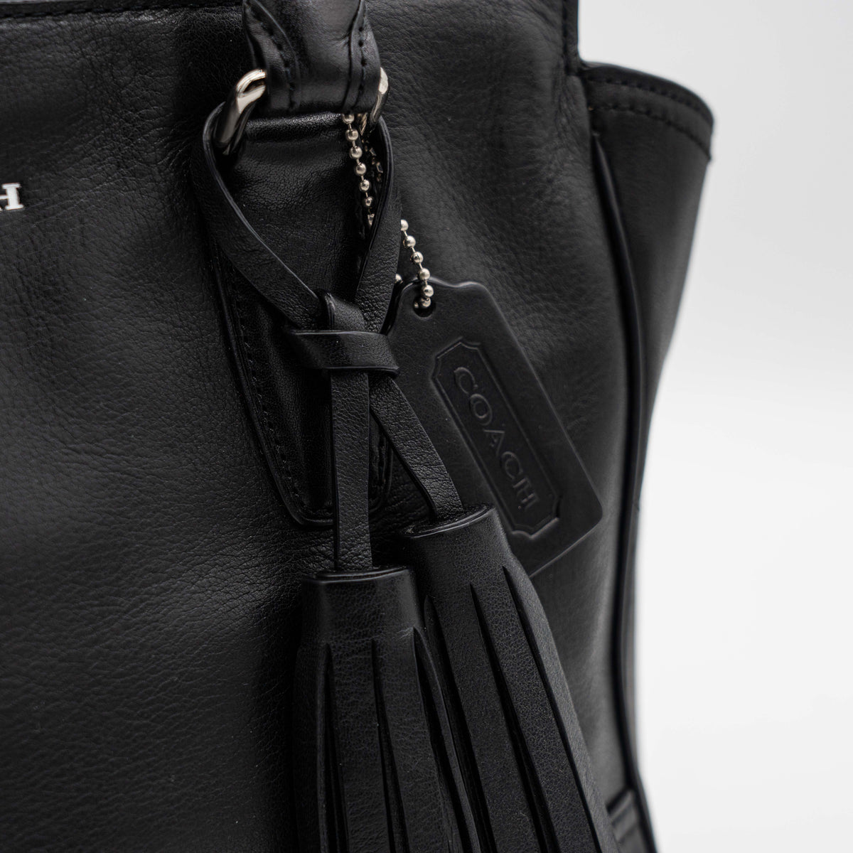 Coach Legacy Candace Carryall in black leather with double tassel charm and silver hardware, photographed against a white background.