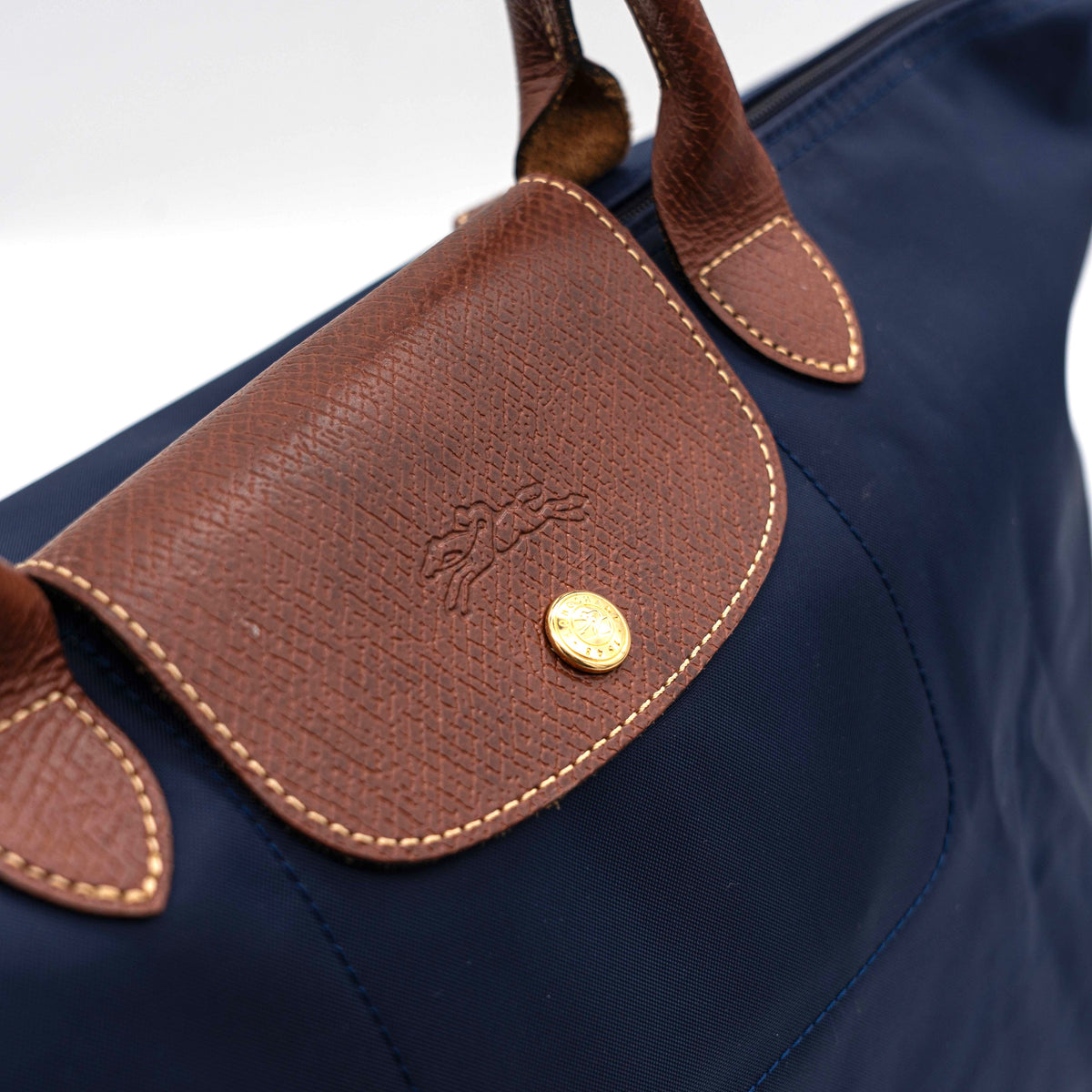 Longchamp Le Pliage Original handbag in navy blue nylon with brown leather handles and trim, shown against a white background.