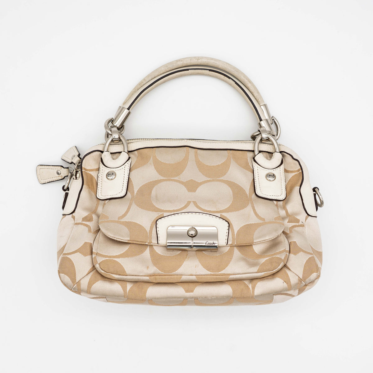Coach Signature Kristin Satchel handbag in beige and cream jacquard with leather trim and detachable strap, displayed against a white background.