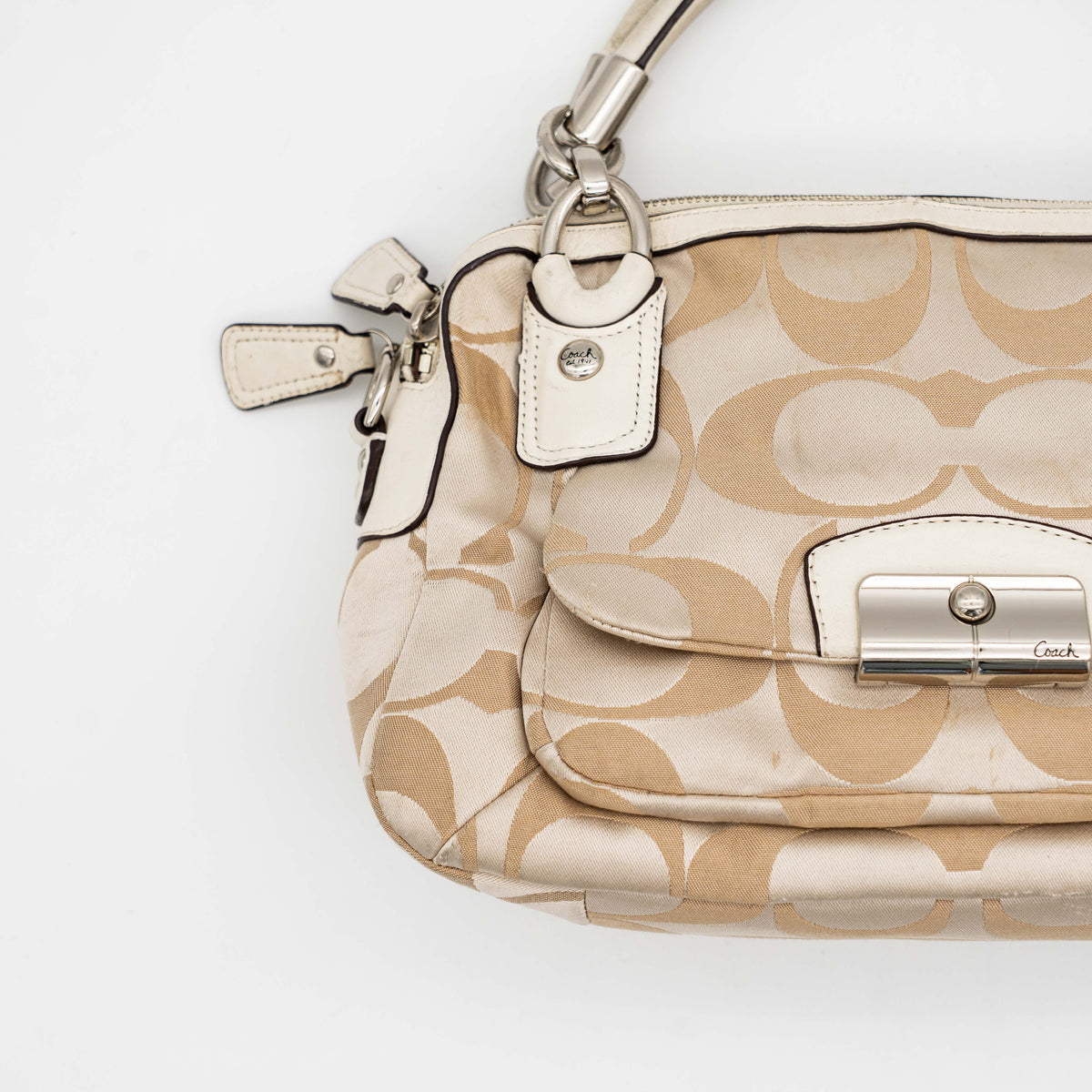 Coach Signature Kristin Satchel handbag in beige and cream jacquard with leather trim and detachable strap, displayed against a white background.