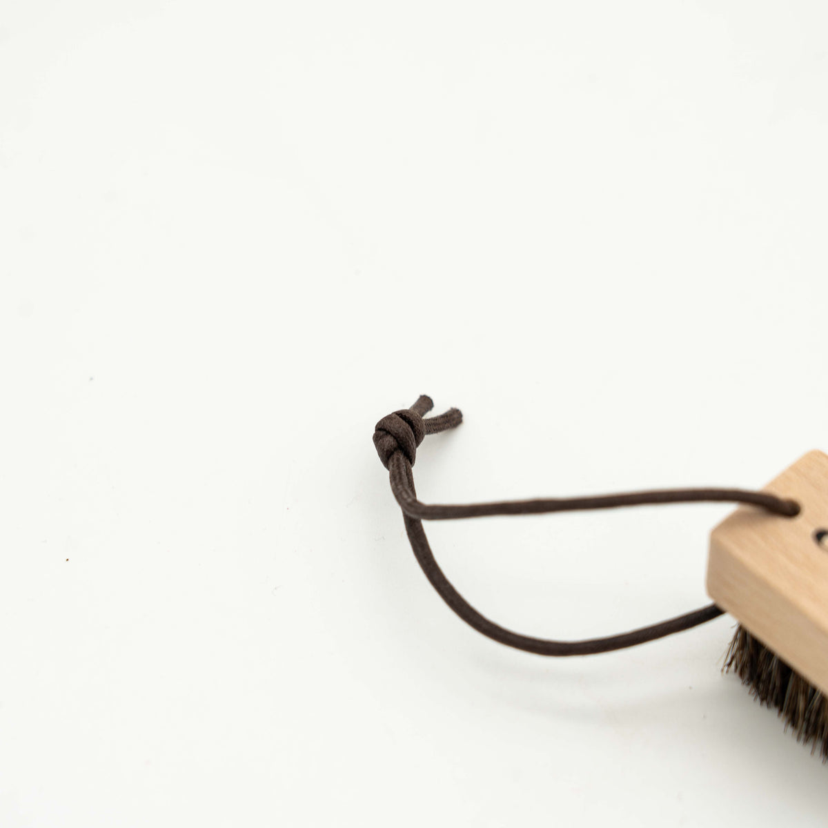 Coach horsehair leather care brush with wood handle and brown bristles, featuring a Coach logo and leather cord loop.