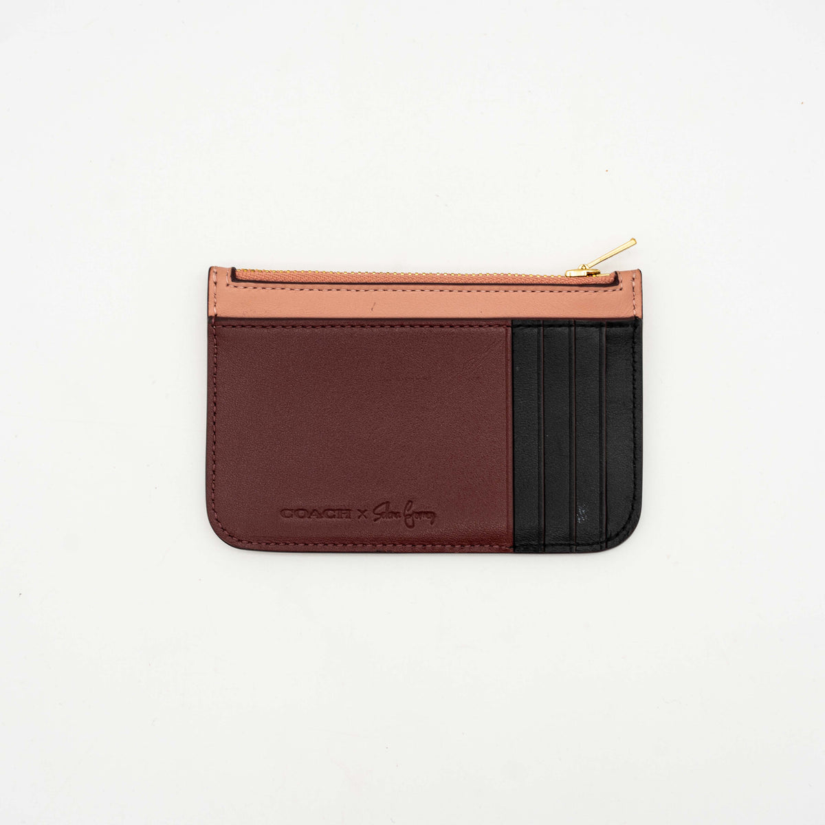 Coach x Selena Gomez colorblock zip card case in pink, burgundy, and black leather with gold hardware and script detail.