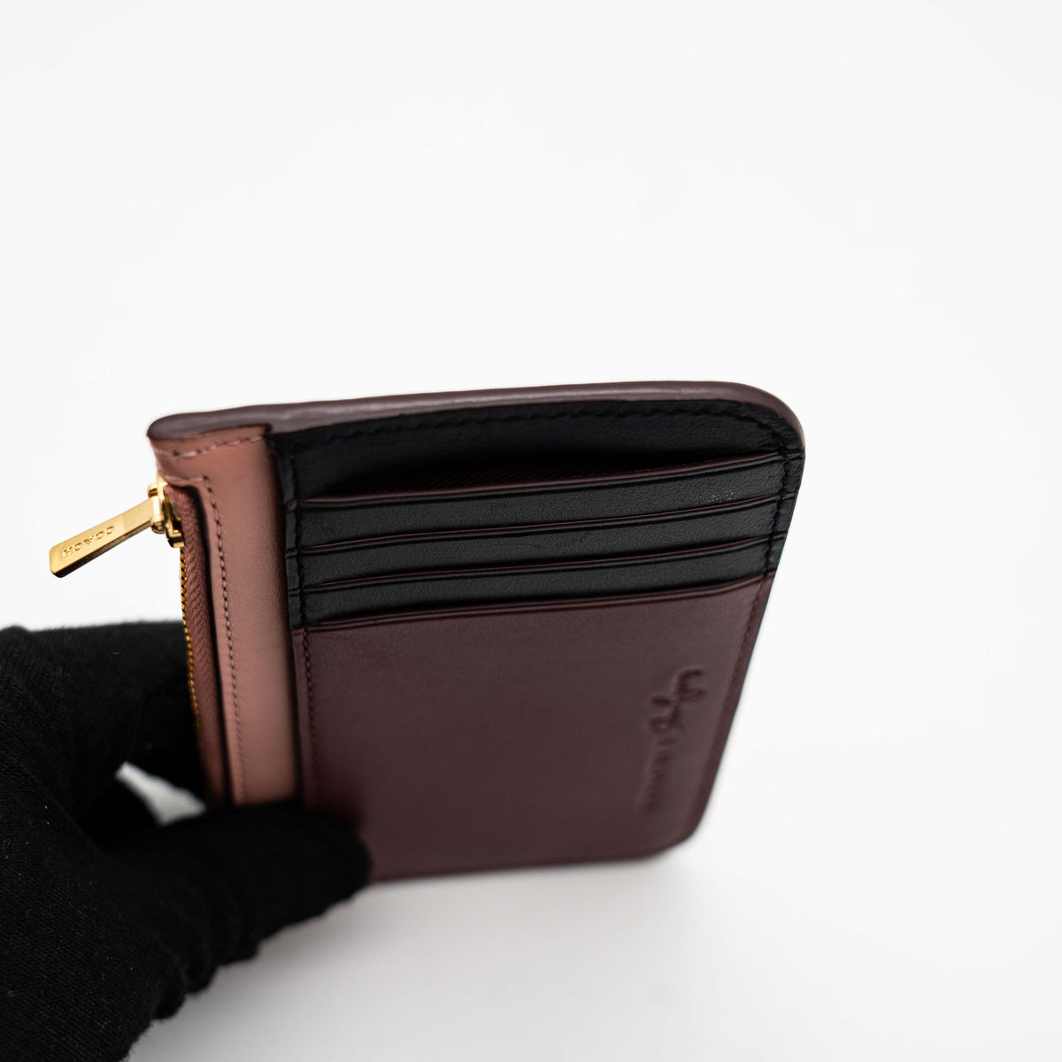 Coach x Selena Gomez colorblock zip card case in pink, burgundy, and black leather with gold hardware and script detail.