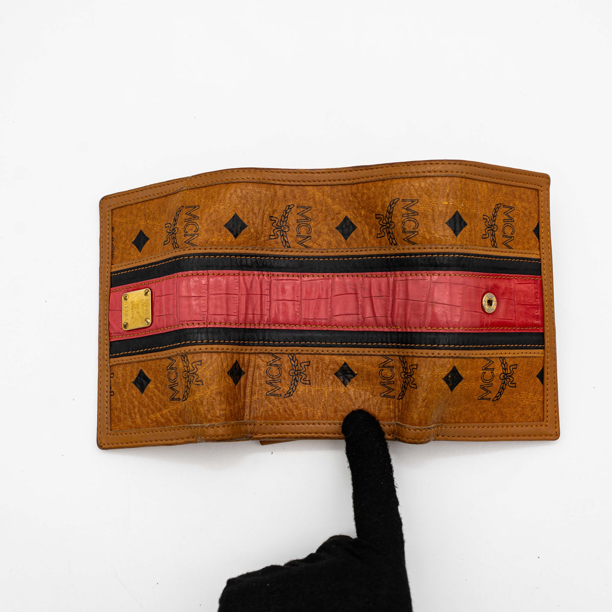 Front view of the MCM Cognac Visetos Monogram Stripe Trifold Wallet in brown with red and black accents and gold logo plaque.