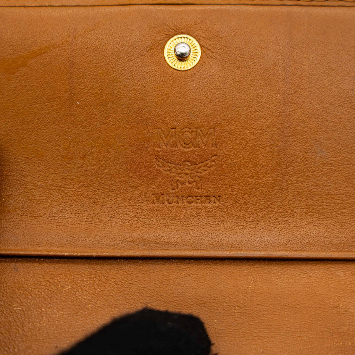 Front view of the MCM Cognac Visetos Monogram Stripe Trifold Wallet in brown with red and black accents and gold logo plaque.