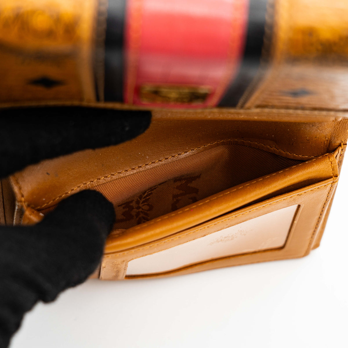 Front view of the MCM Cognac Visetos Monogram Stripe Trifold Wallet in brown with red and black accents and gold logo plaque.