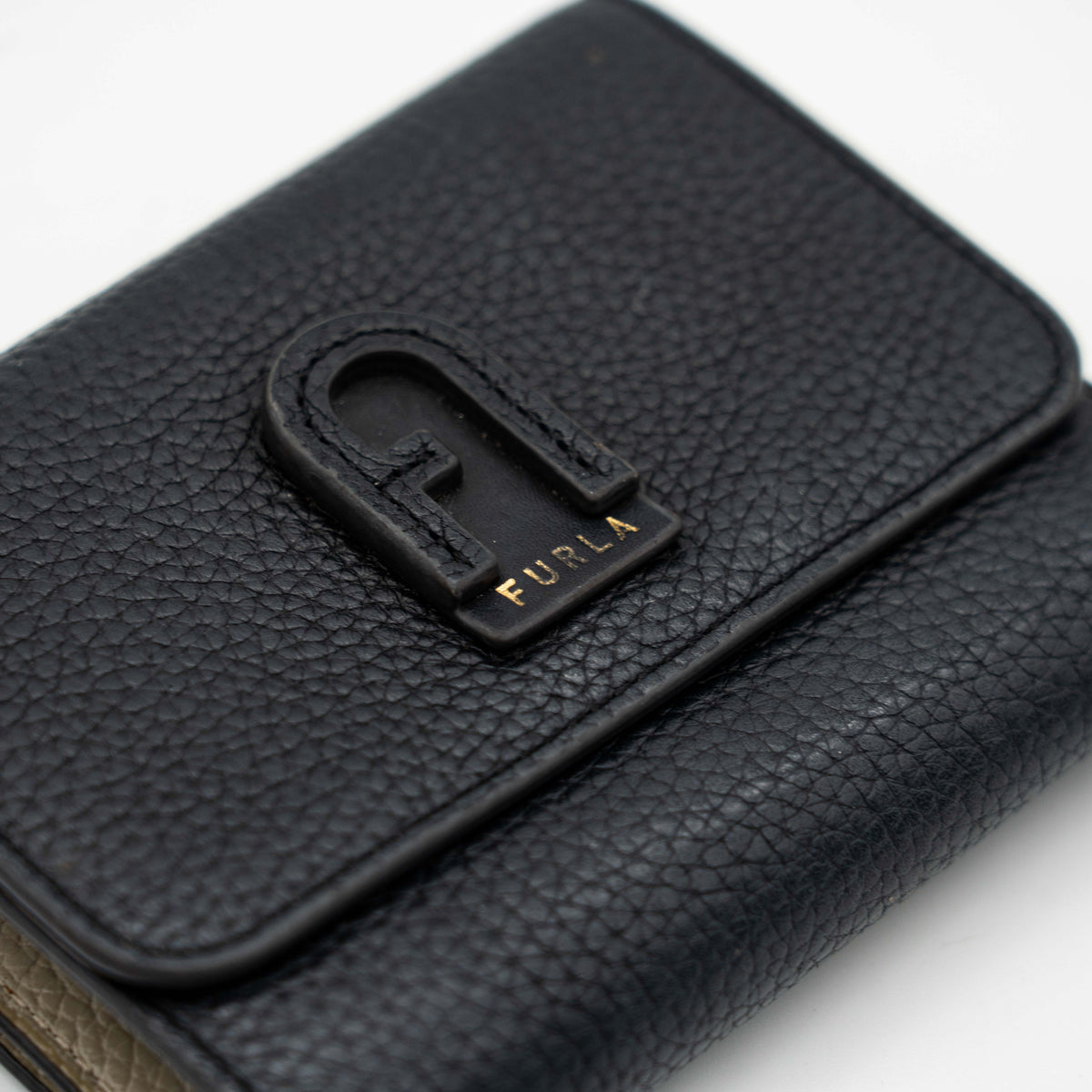 Furla Dafne black trifold wallet in pebbled leather with gold-tone hardware and logo plaque on the front.