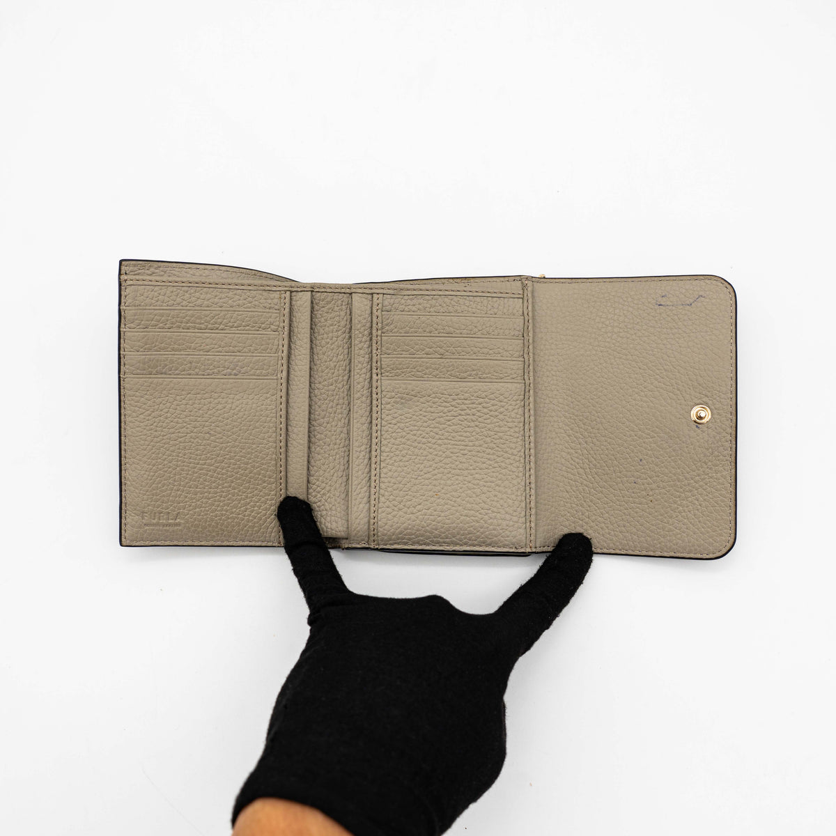 Furla Dafne black trifold wallet in pebbled leather with gold-tone hardware and logo plaque on the front.