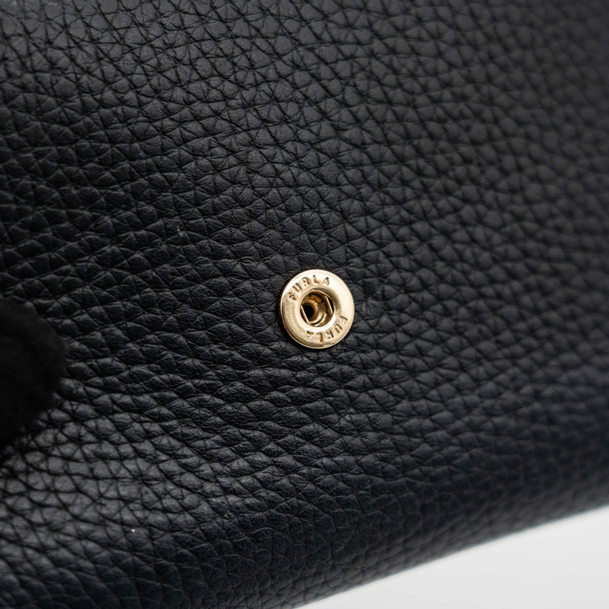 Furla Dafne black trifold wallet in pebbled leather with gold-tone hardware and logo plaque on the front.