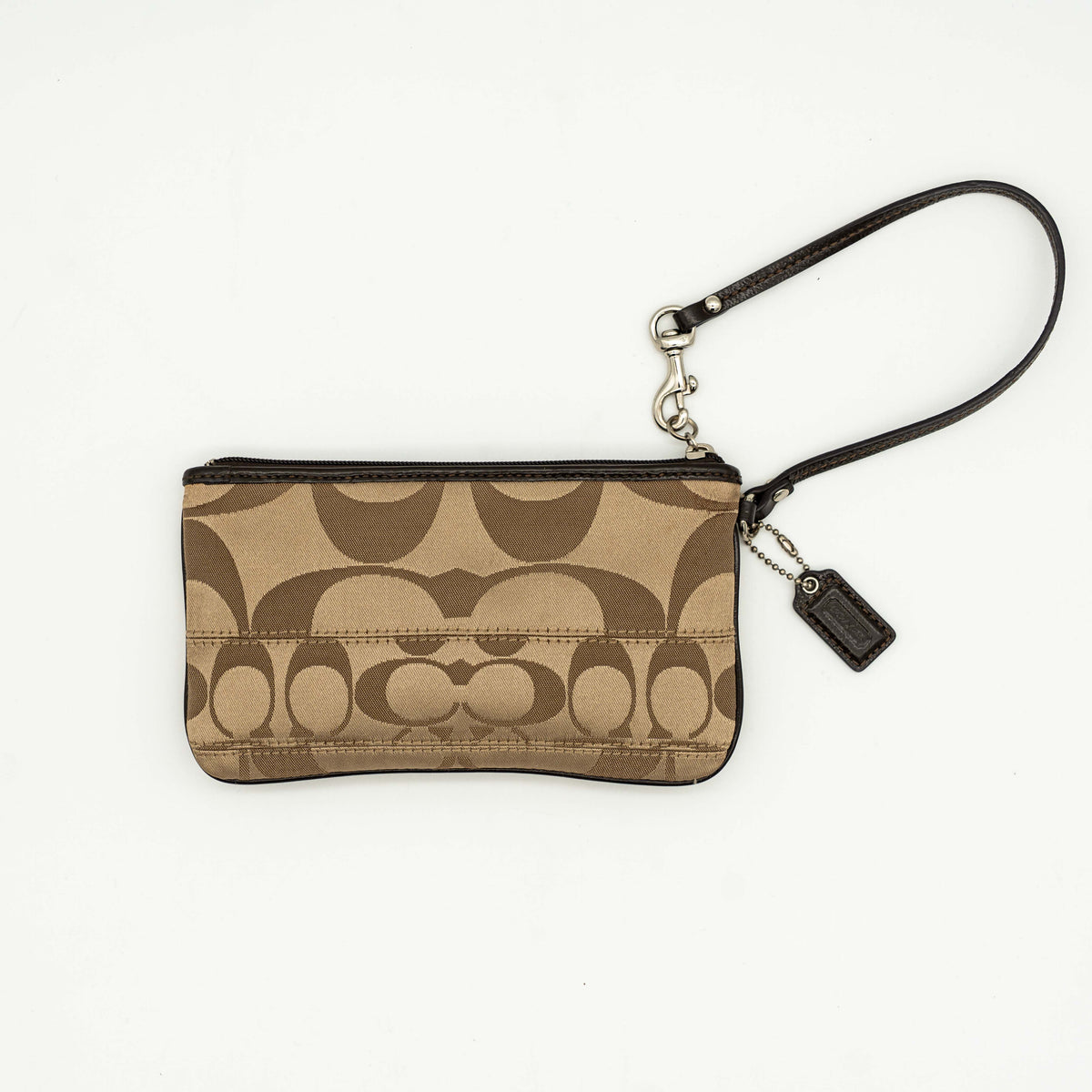 Coach brown monogram wristlet with silver badge and detachable leather strap, photographed on a white background.