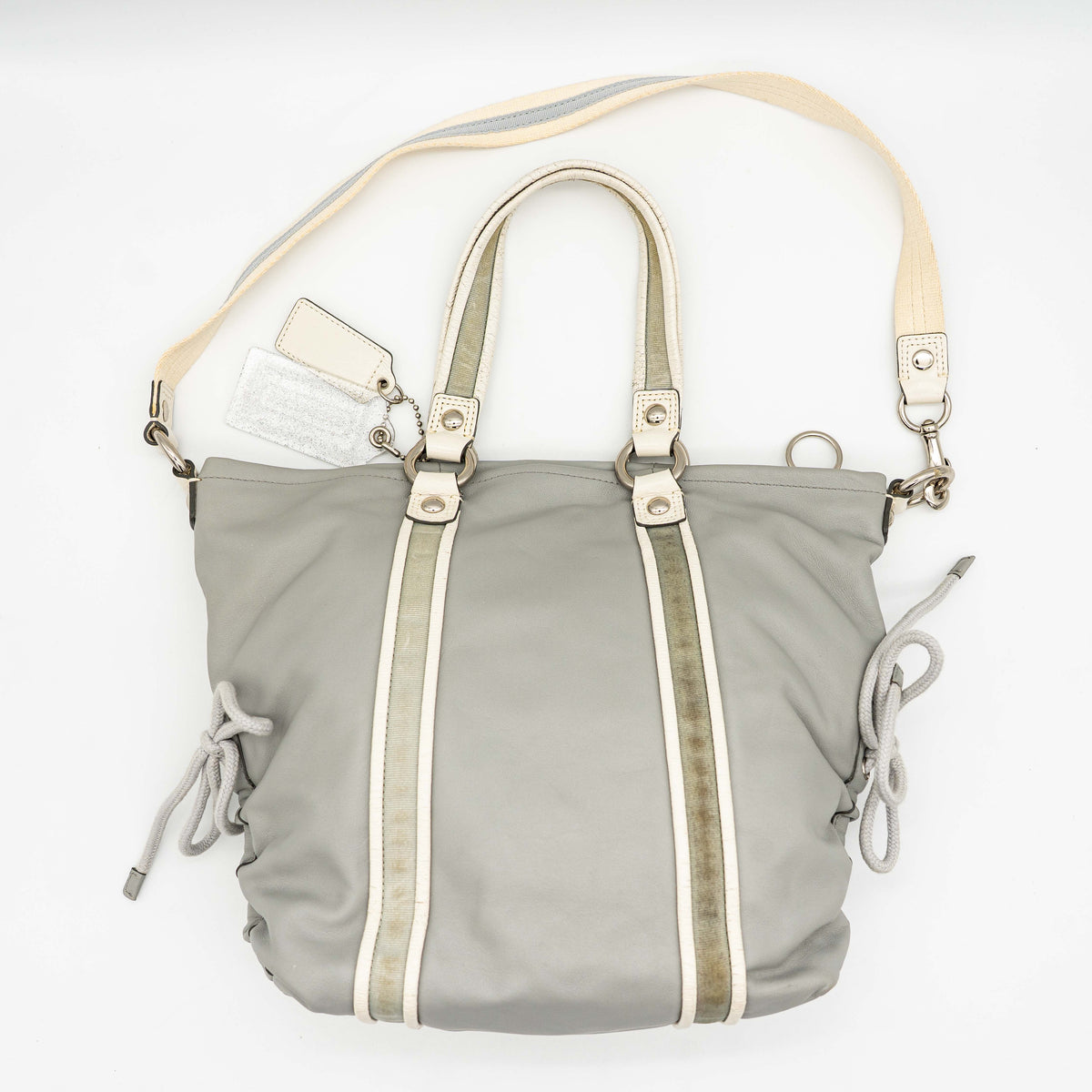 Coach Poppy Spotlight grey shoulder bag with double top handles, white trim, and detachable webbing strap, displayed on a white background.