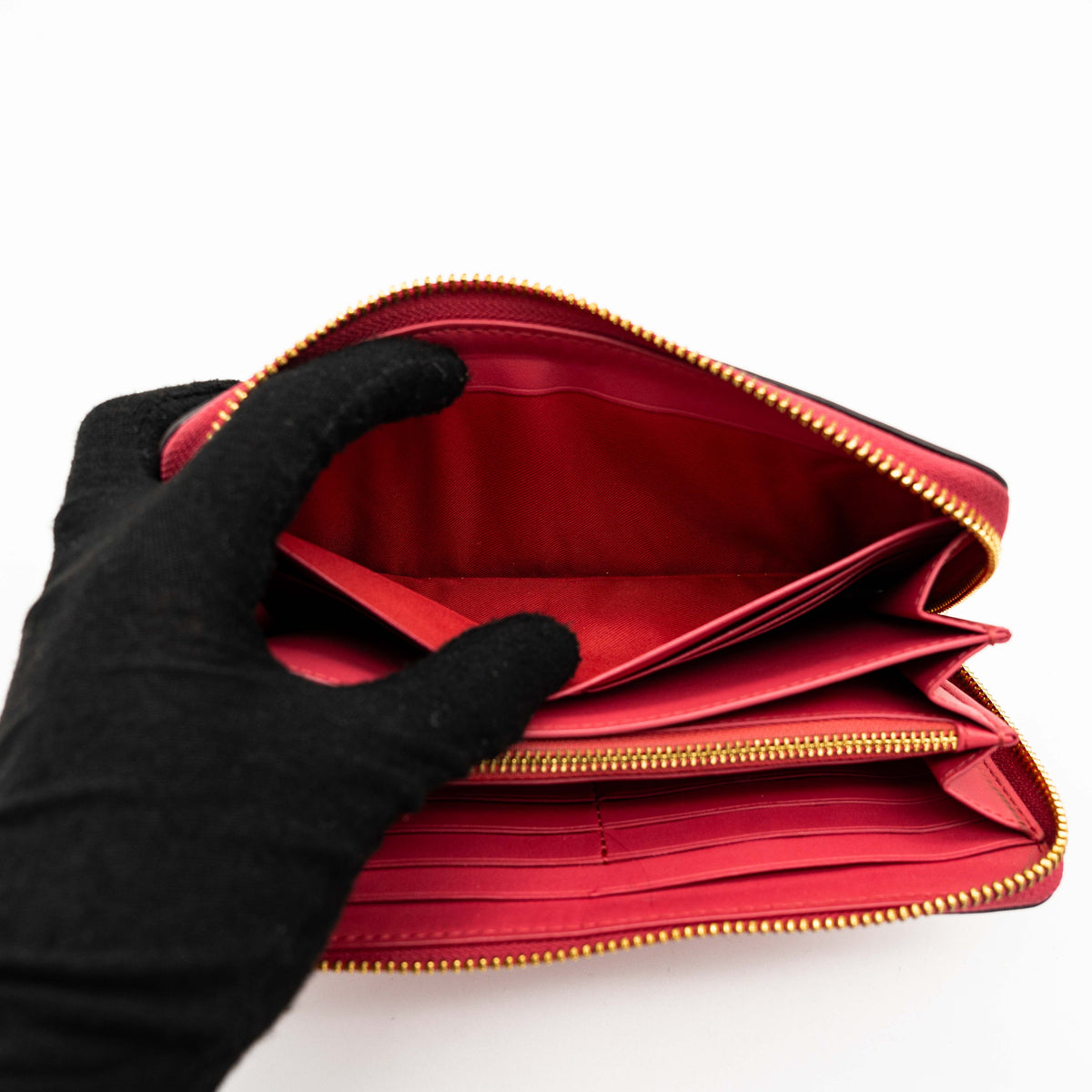 Coach Horse And Carriage Long Zip Around Wallet in red grained leather with gold-tone hardware and embossed logo, shown against a white background.