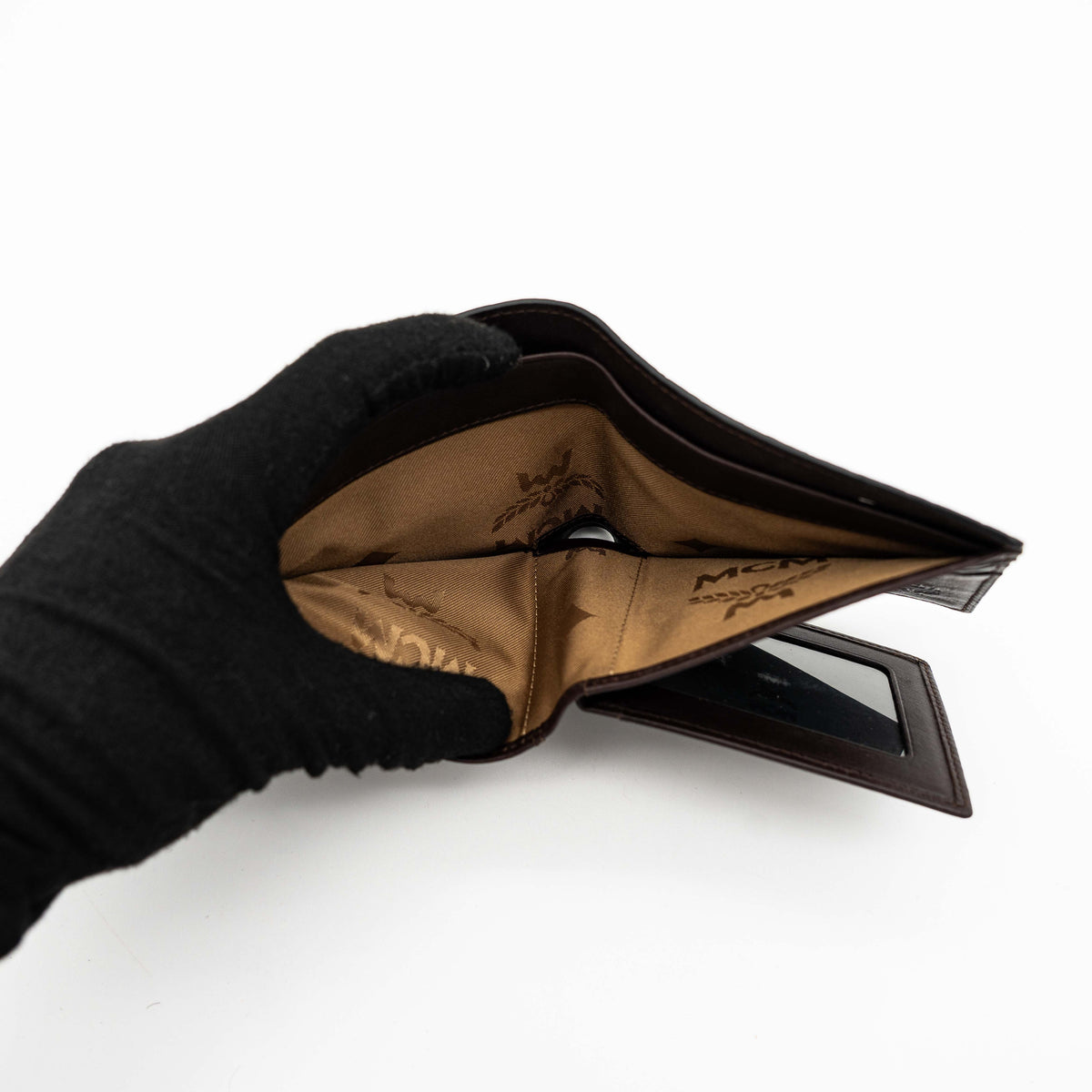 MCM dark brown leather bifold wallet with embossed Visetos monogram pattern shown against a white background.