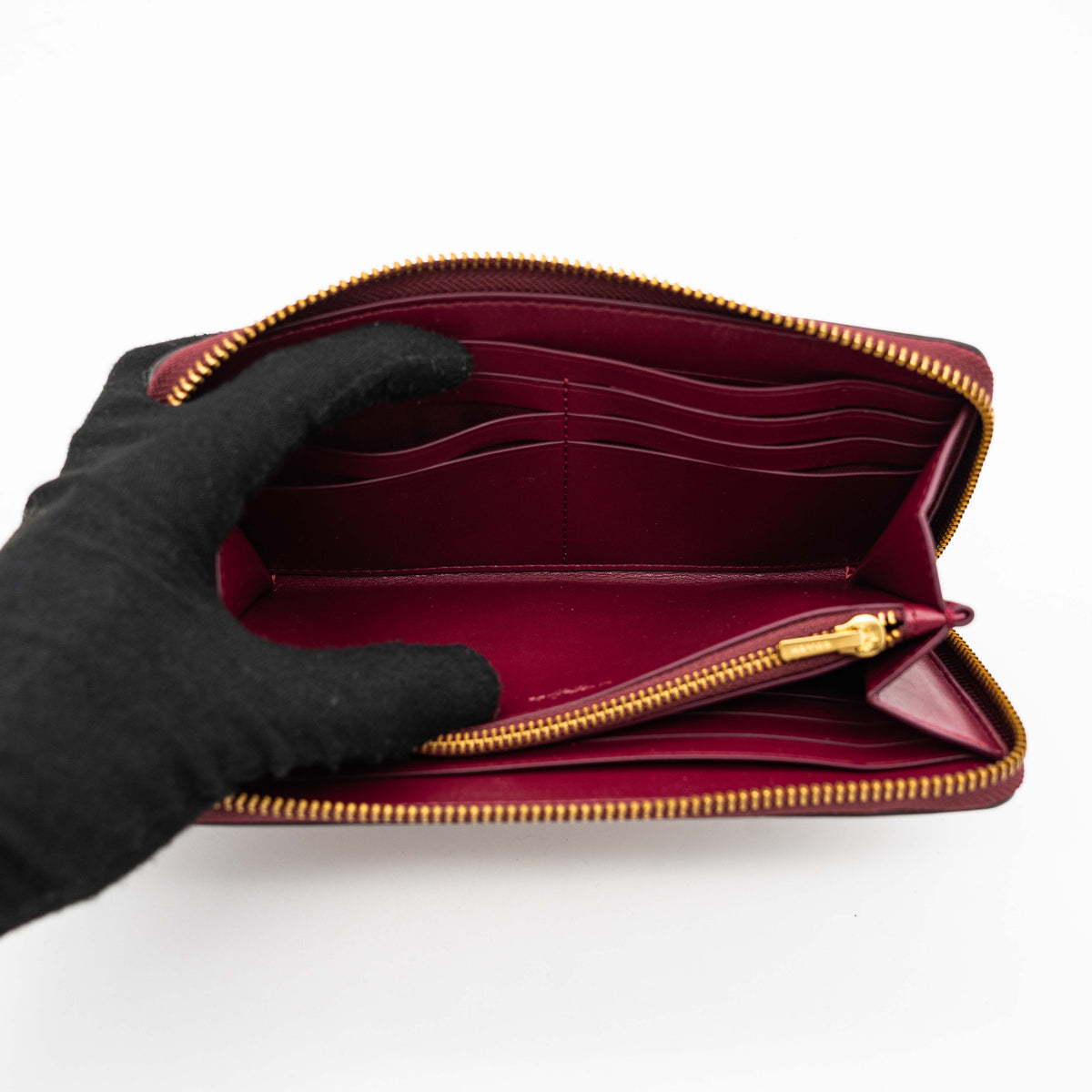 Coach Signature Accordion Zip Wallet in burgundy monogram canvas with leather trim and gold zip, photographed against a clean white background.