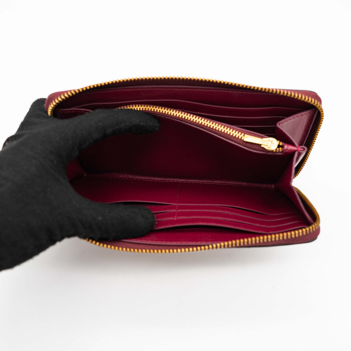 Coach Signature Accordion Zip Wallet in burgundy monogram canvas with leather trim and gold zip, photographed against a clean white background.