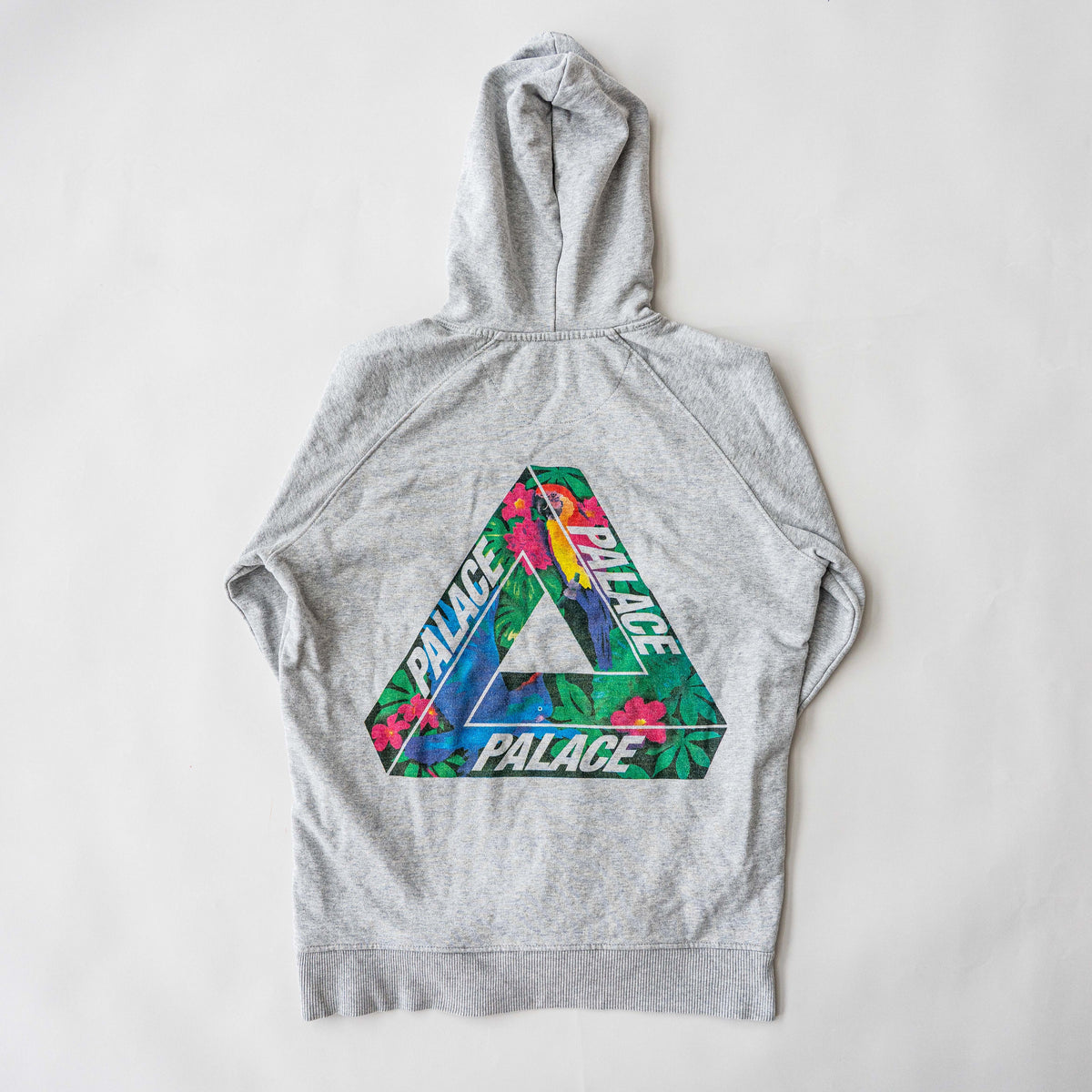 Palace grey pullover hoodie with tropical Tri-Ferg back graphic and white chest logo, laid flat on a neutral background.