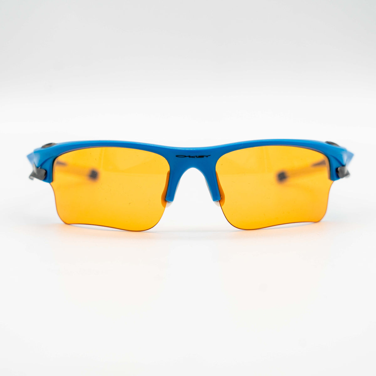 Oakley Fast Jacket OO9156-04 sunglasses in blue with orange lenses, displayed with two extra pairs of lenses, cleaning cloth and a black Oakley hard case.