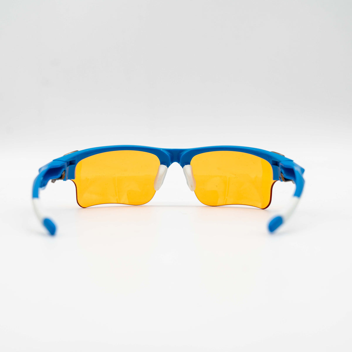 Oakley Fast Jacket OO9156-04 sunglasses in blue with orange lenses, displayed with two extra pairs of lenses, cleaning cloth and a black Oakley hard case.