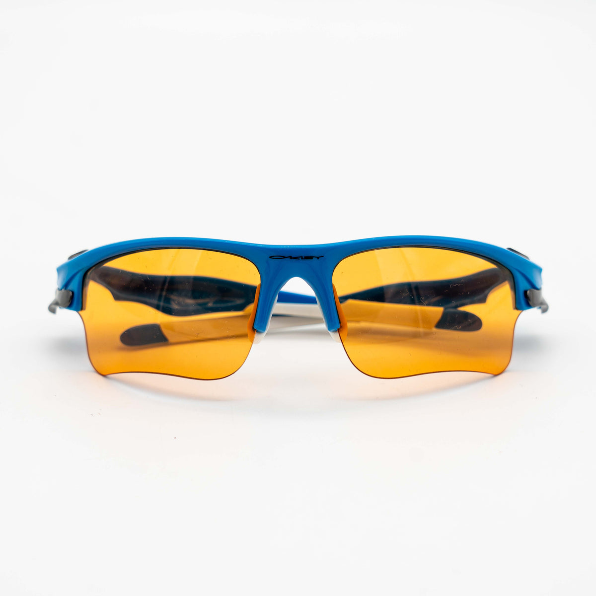 Oakley Fast Jacket OO9156-04 sunglasses in blue with orange lenses, displayed with two extra pairs of lenses, cleaning cloth and a black Oakley hard case.