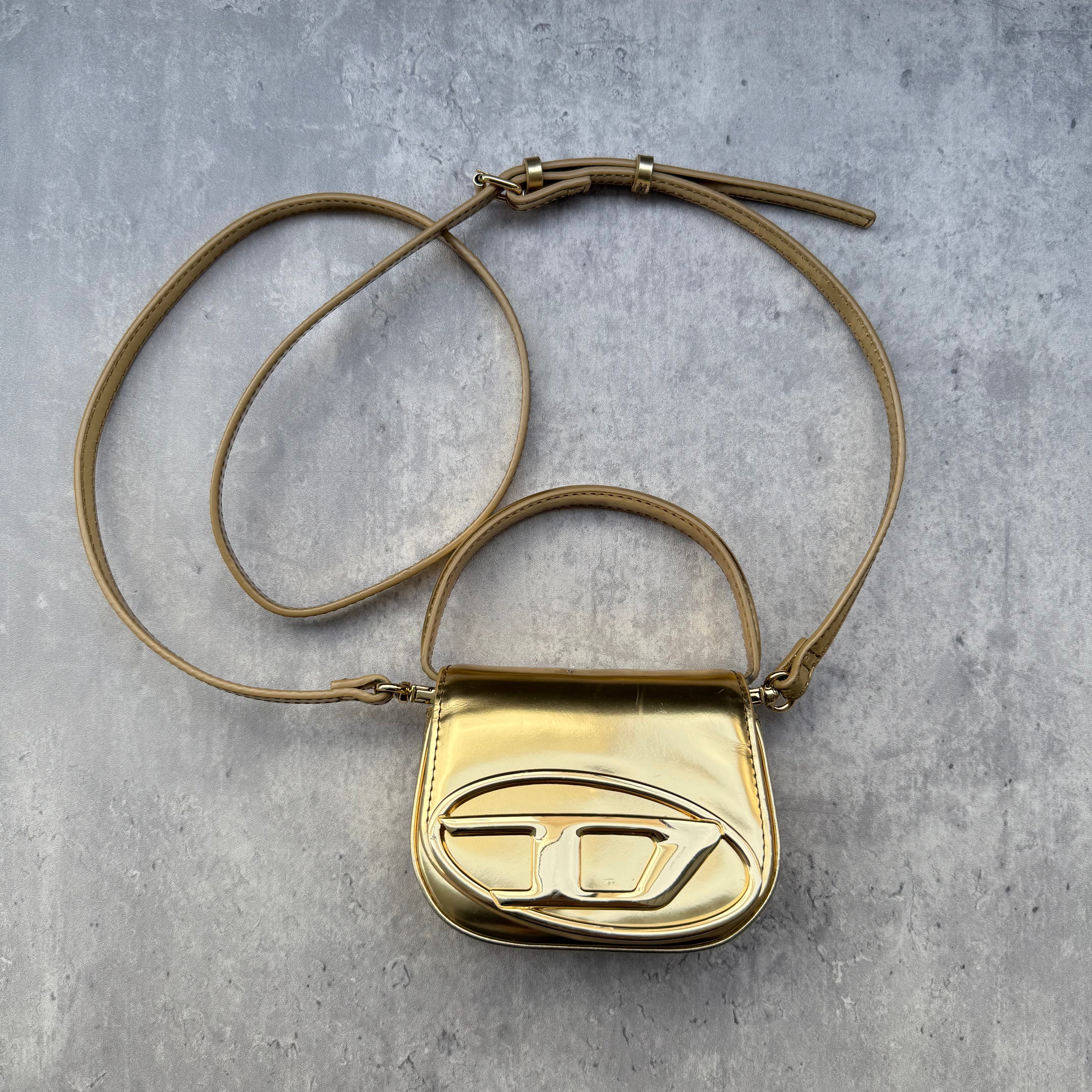 Diesel 1DR-XS-S Mini Bag in metallic gold with signature D logo plaque, detachable strap, and structured silhouette