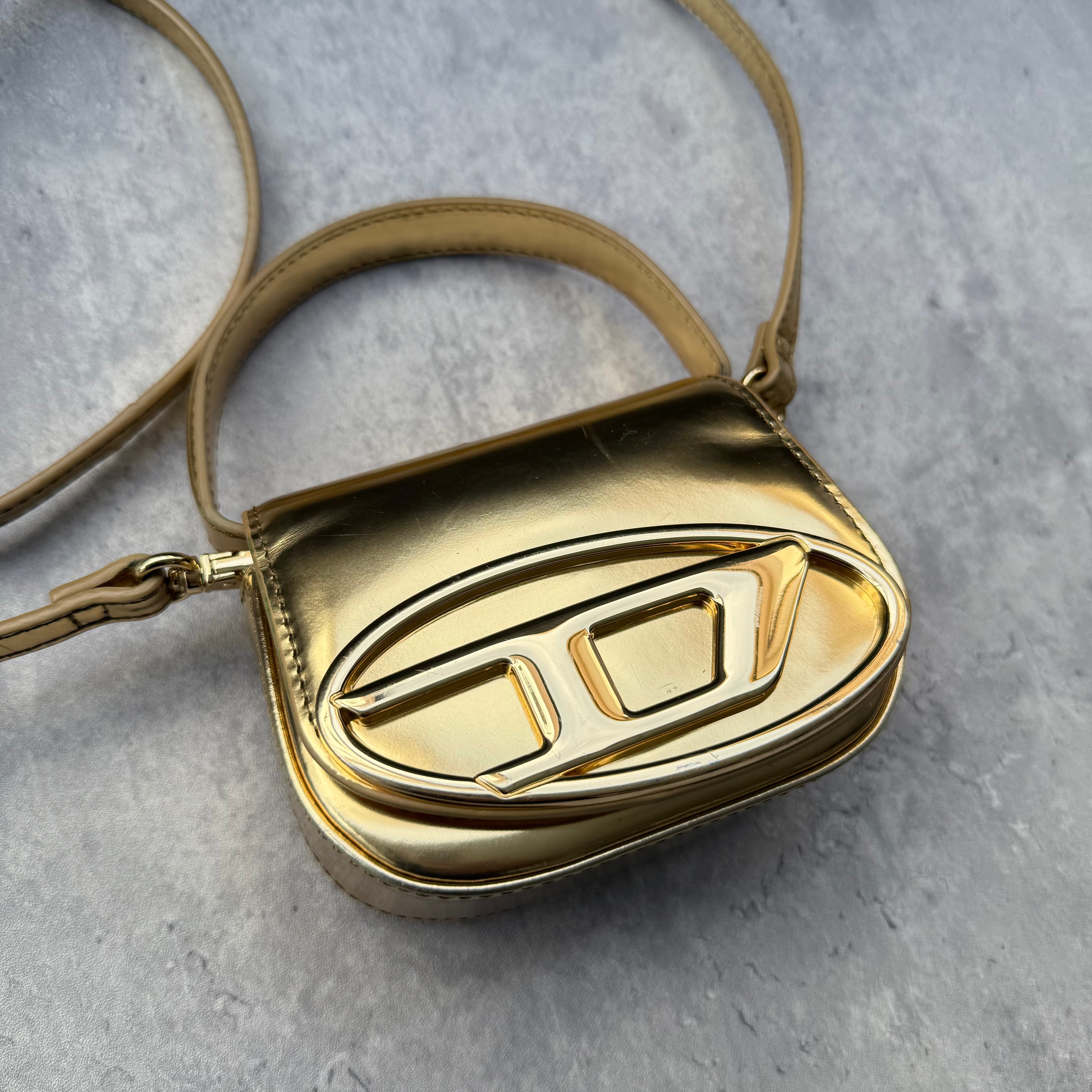 Diesel 1DR-XS-S Mini Bag in metallic gold with signature D logo plaque, detachable strap, and structured silhouette