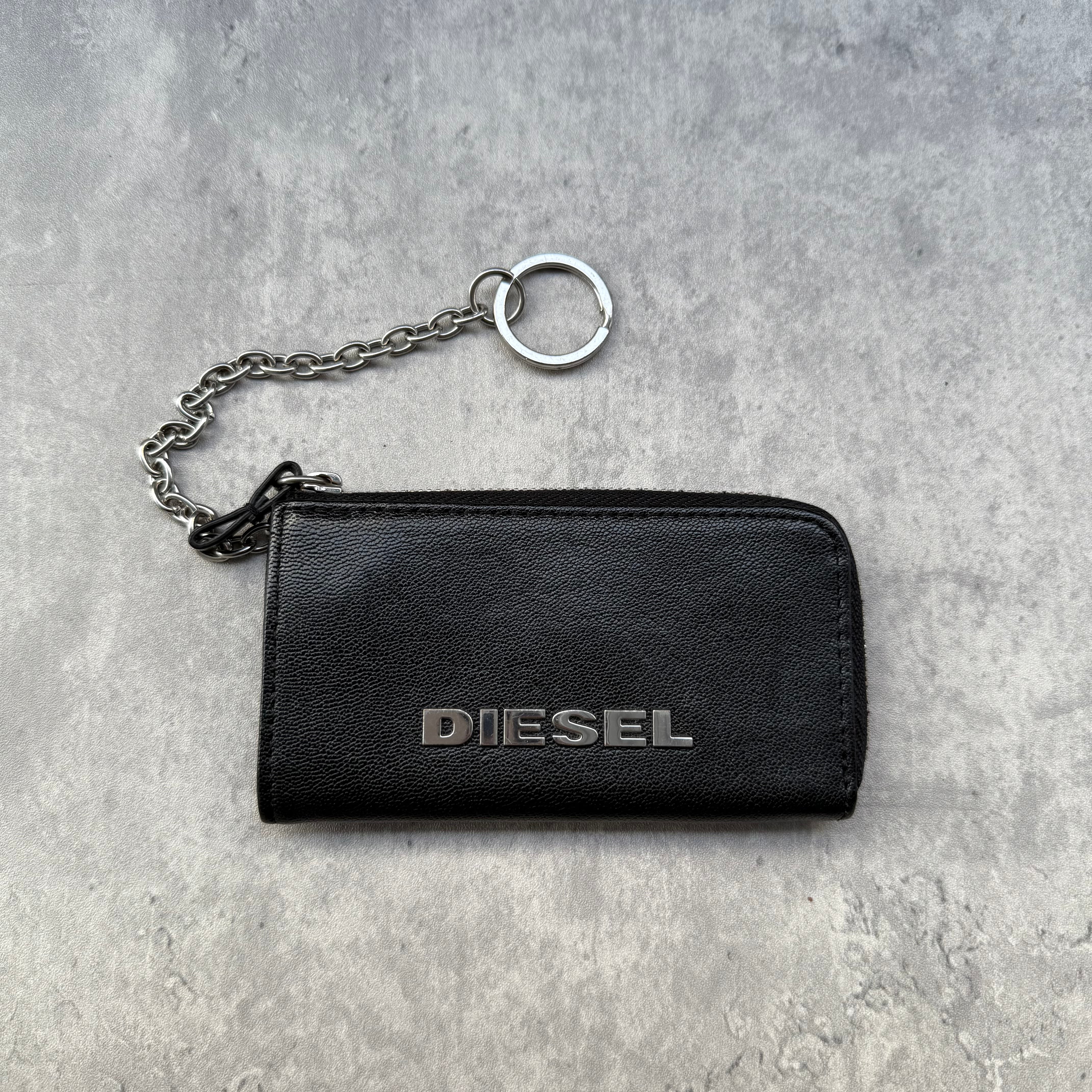 Diesel Key Coin Case Wallet in black leather with silver logo, zip closure, and attached chain keyring.