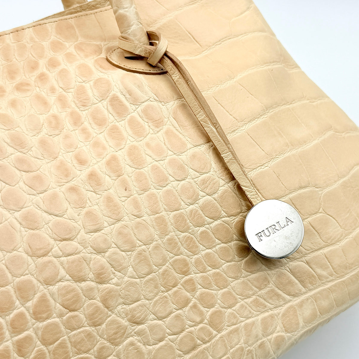 Furla beige croc-embossed leather handbag with double handles and silver-tone logo medallion, photographed on a white background.