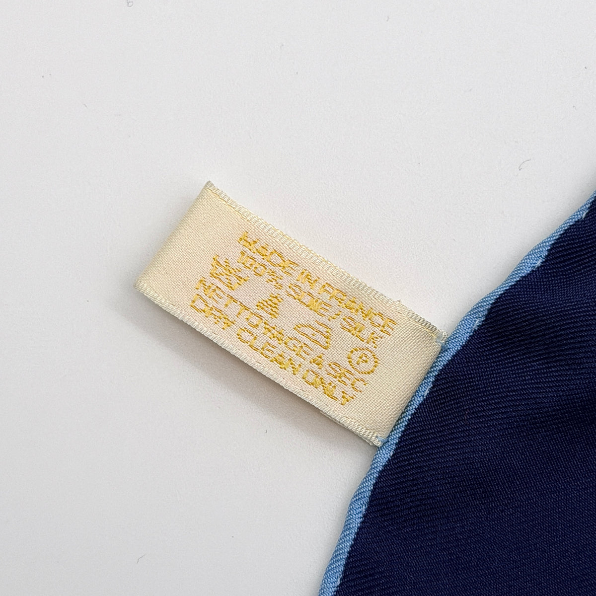 Cartier silk scarf in blue and white with graphic monogram logo print and navy border, elegantly arranged.