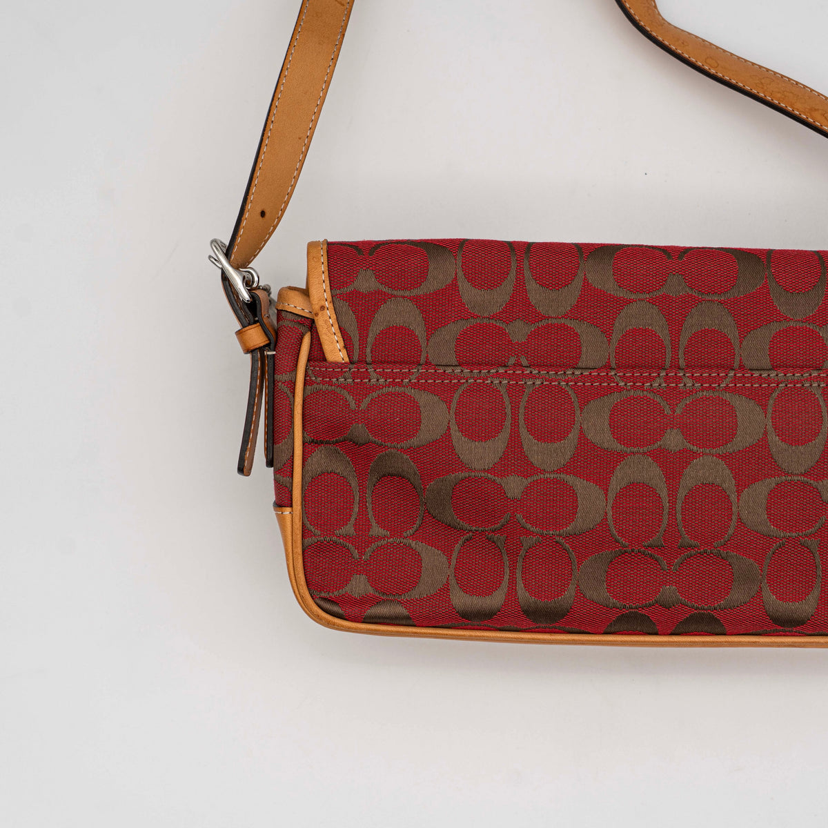 Coach Signature Soho Buckle Baguette in red and tan canvas with leather trim and a silver buckle, shown on a white background.