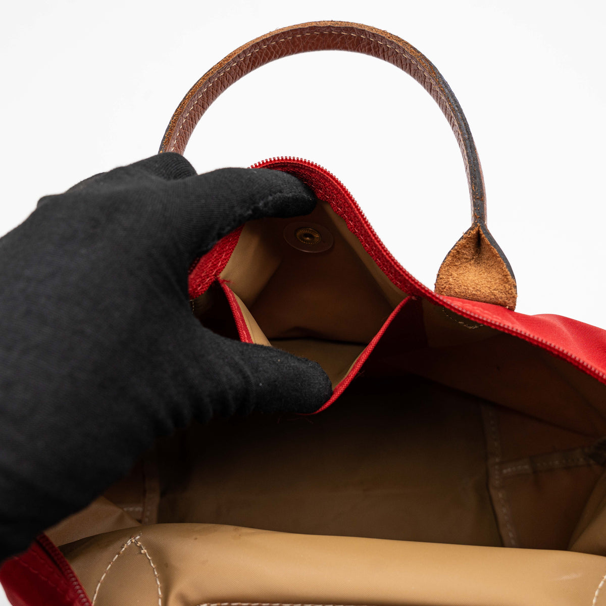 Longchamp Le Pliage handbag in red nylon with brown leather handles and gold-tone accents, photographed on a white background.