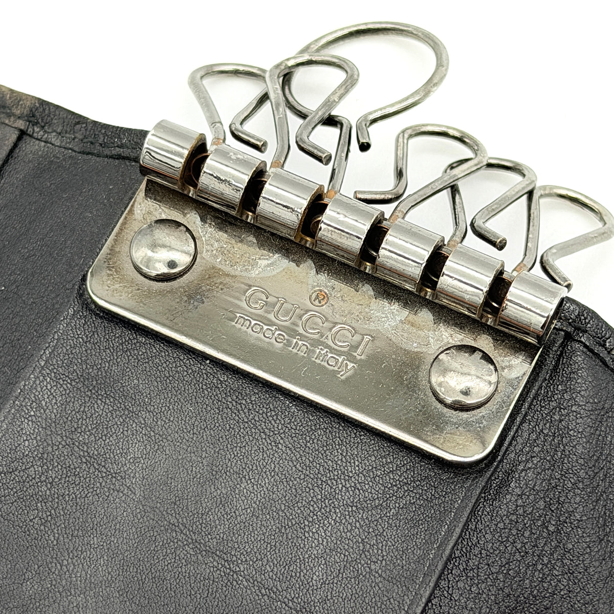 Gucci Guccissima GG Monogram black leather key case with silver-tone hardware, shown closed against a white background.