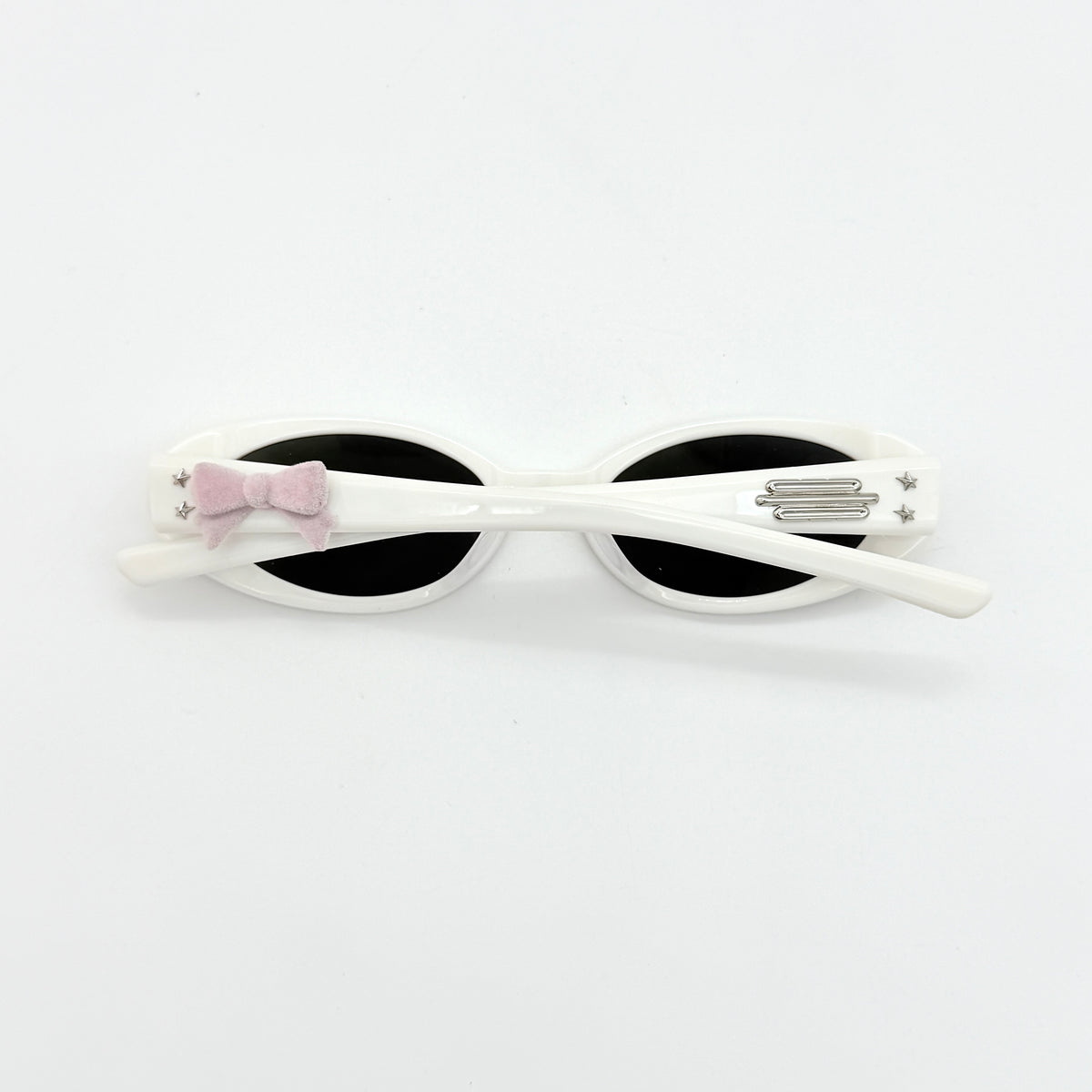 Gentle Monster x Jennie Hush W2 oval sunglasses in white with a pink bow charm, styled with the signature pink furry case.