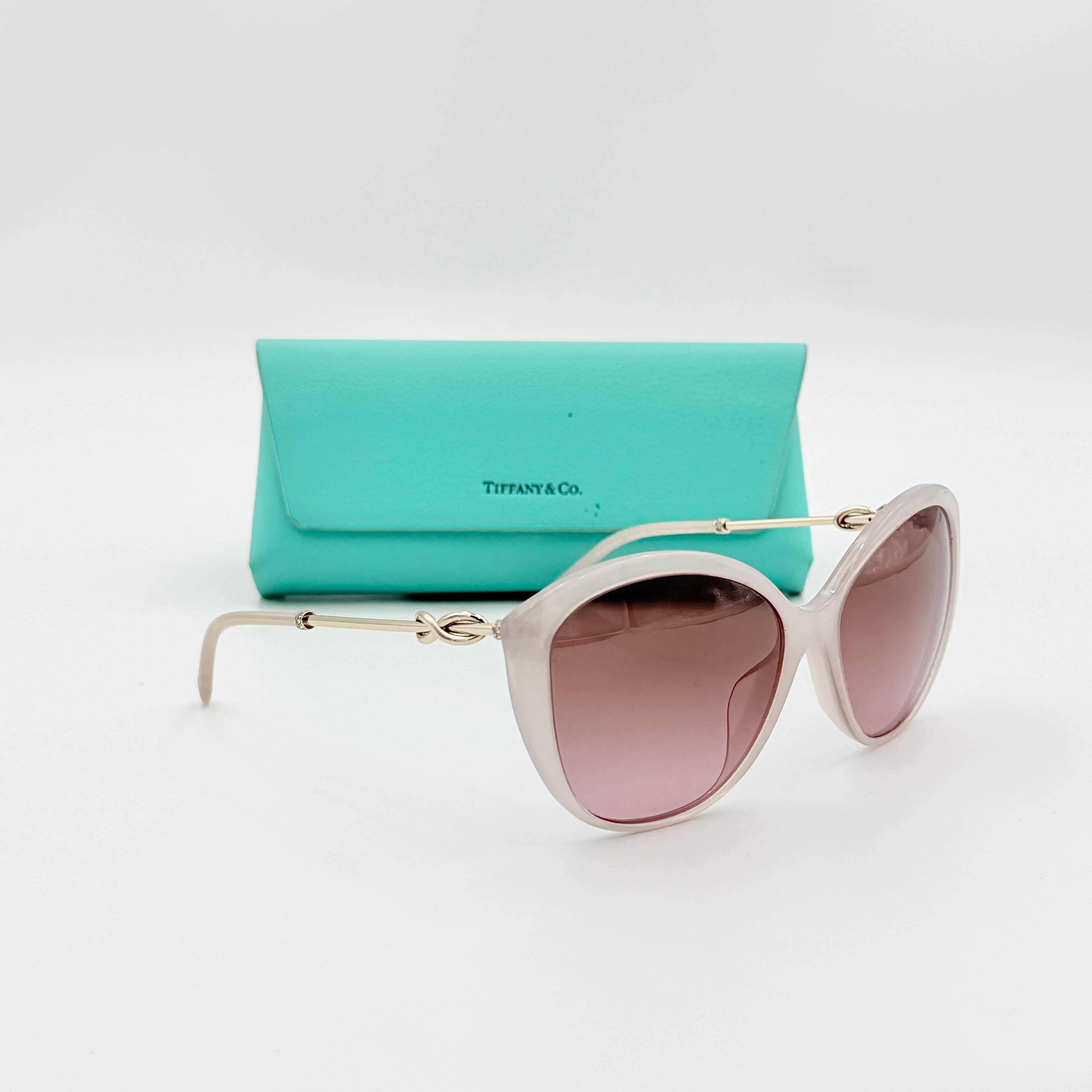 Tiffany & Co. TF4144 sunglasses in pink with gold-tone knot detail arms, shown with signature blue case.