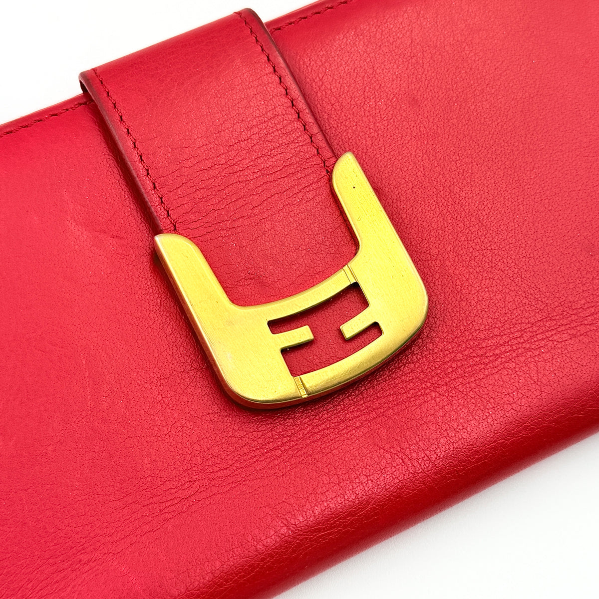 Fendi FF Logo Buckle Flap Continental Wallet in red leather with gold hardware, displayed closed on a white background.