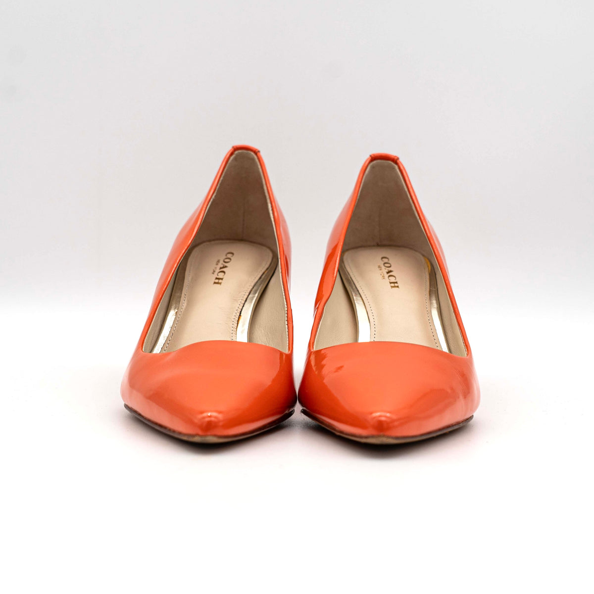Pair of Coach orange patent leather pointed-toe heels with gold logo detail, size EU 35.5.