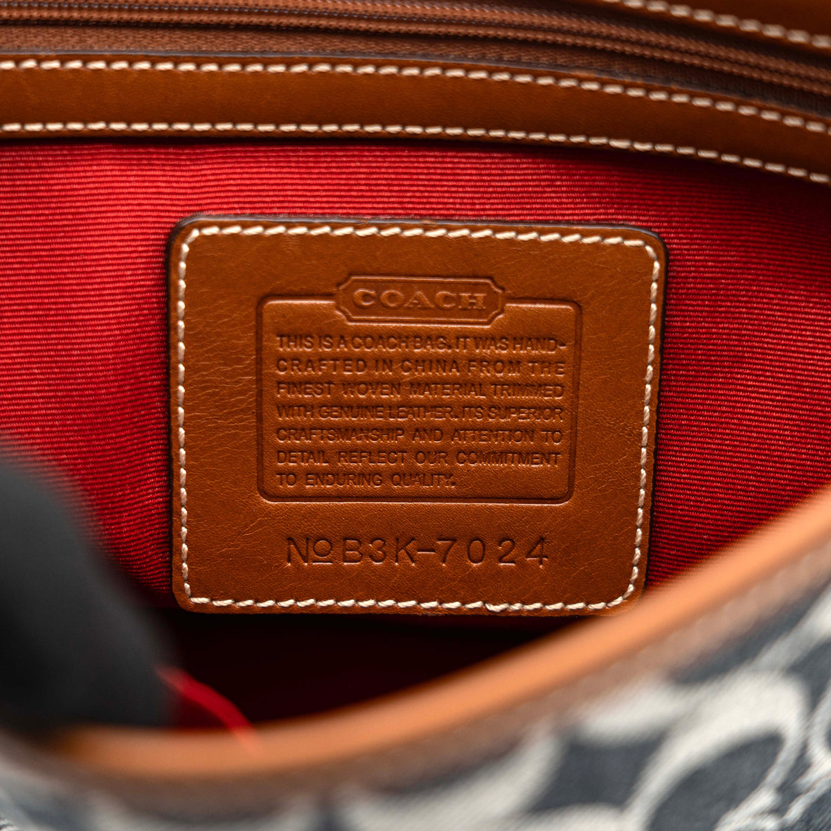 Coach signature denim hobo crossbody bag with red and blue stripe, brown leather trim, and an adjustable strap.