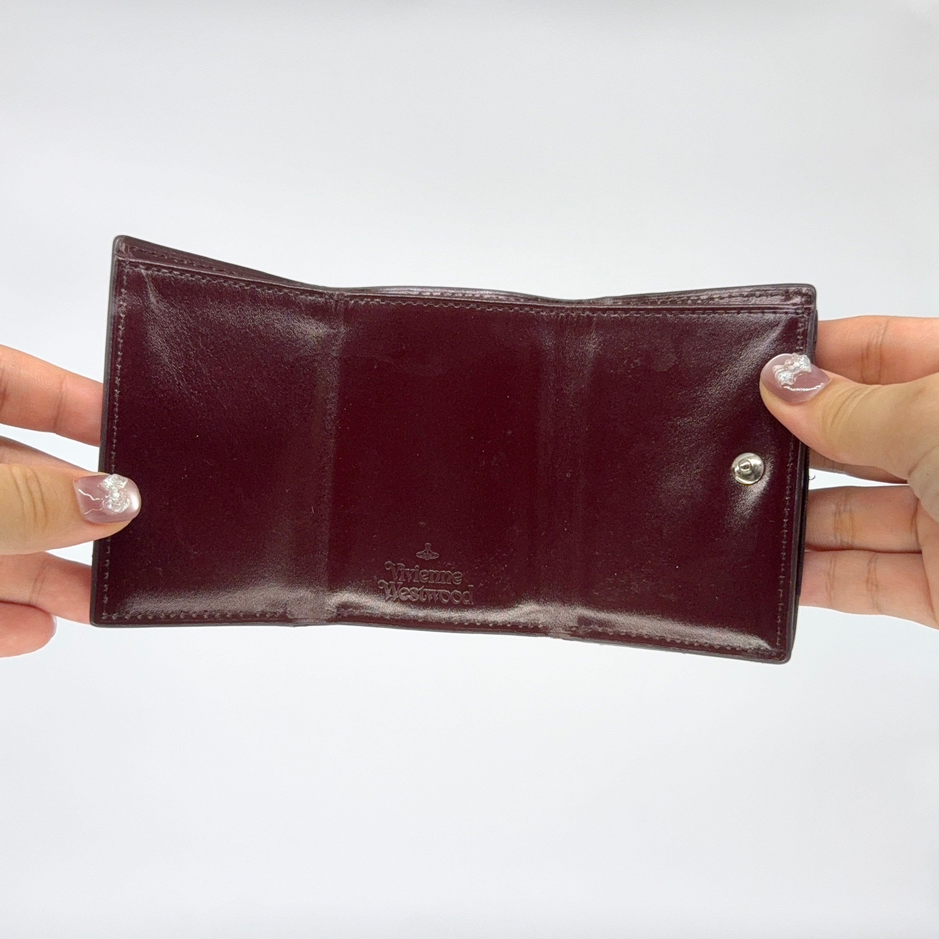 Vivienne Westwood Signature Orb Wallet in glossy purple leather with silver orb emblem on the front flap.